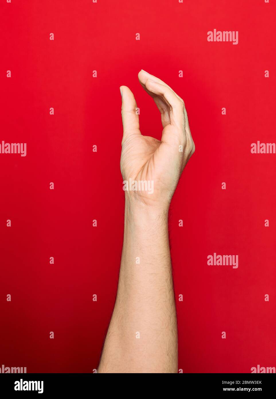 Schöne Hand des Mannes zeigt Finger angehoben tun fangen Geste über isolierten roten Hintergrund Stockfoto