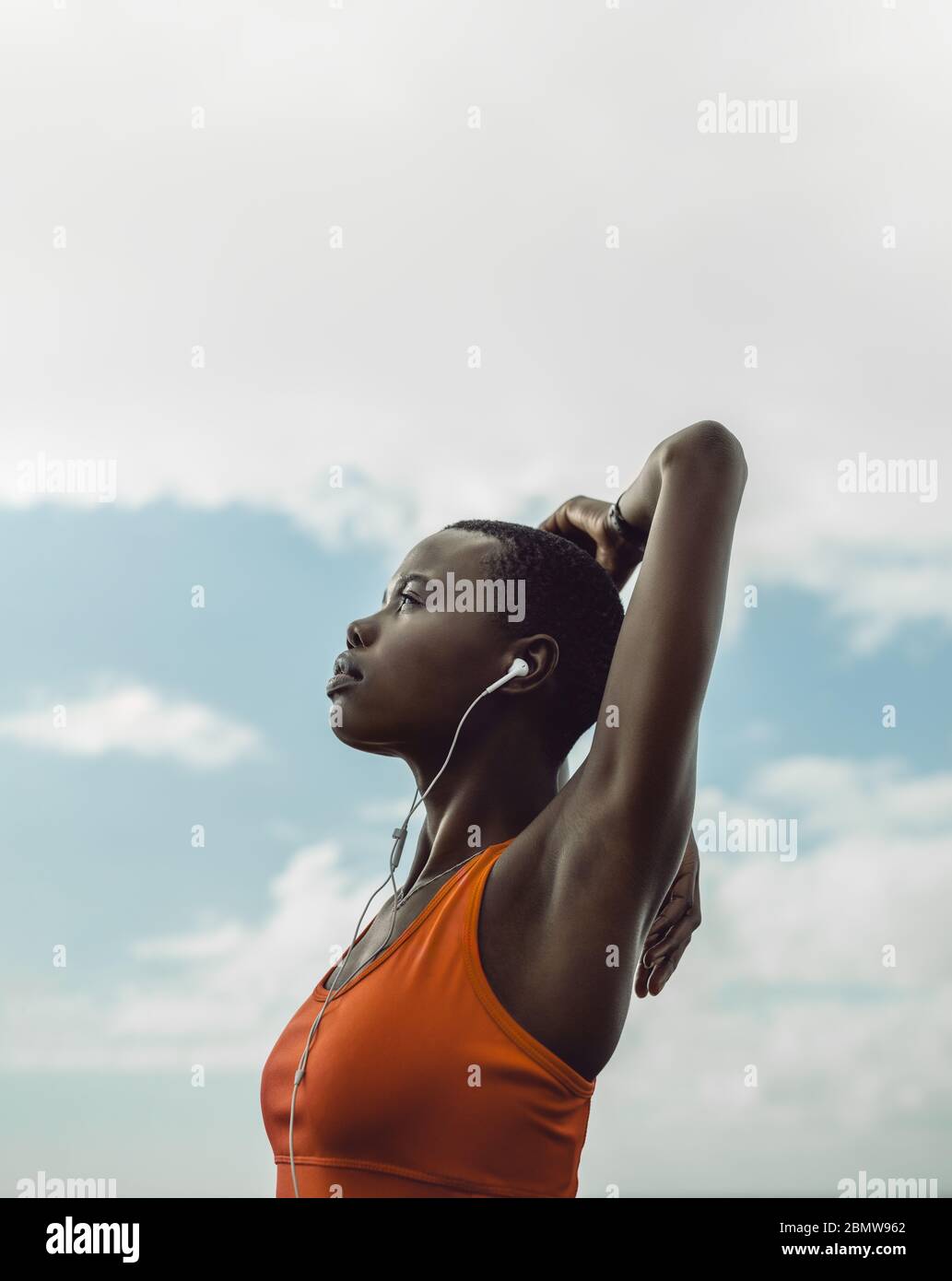 Seitenansicht einer Fitness-Frau mit Armen Stretching Warmup Übung im Freien. Frauen in Sportbekleidung tun erstreckt sich im Freien gegen den Himmel. Stockfoto