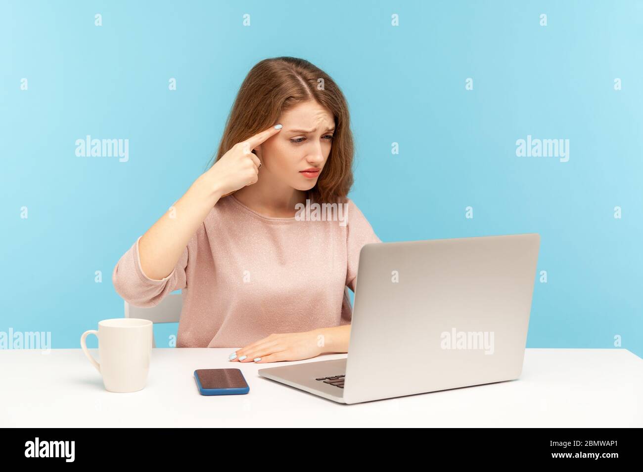 Das ist eine idiotische Idee! Unzufrieden Frau mit sinnlosen dummen Gespräch auf Videoanruf und zeigt dumme Geste auf Laptop-Bildschirm, Finger in der Nähe des Kopfes Stockfoto