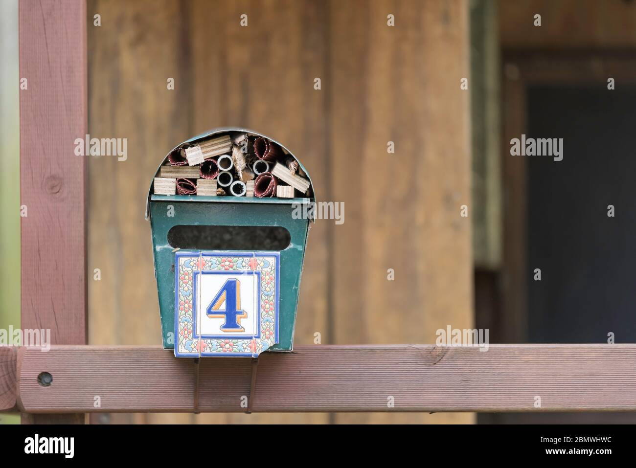Ein alter Hausbriefkasten, der jetzt an ein Hinterhof-Kubbenhaus angeschlossen und mit Holzschrott und Bambusausschnitten in ein Käfer-, Biene- oder Insektenhotel umgewandelt wurde Stockfoto