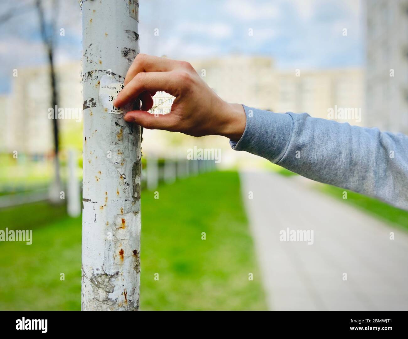 Die Hand des Mannes reißt die alte Anzeige vom Pfosten. Foto auf dem Handy Stockfoto