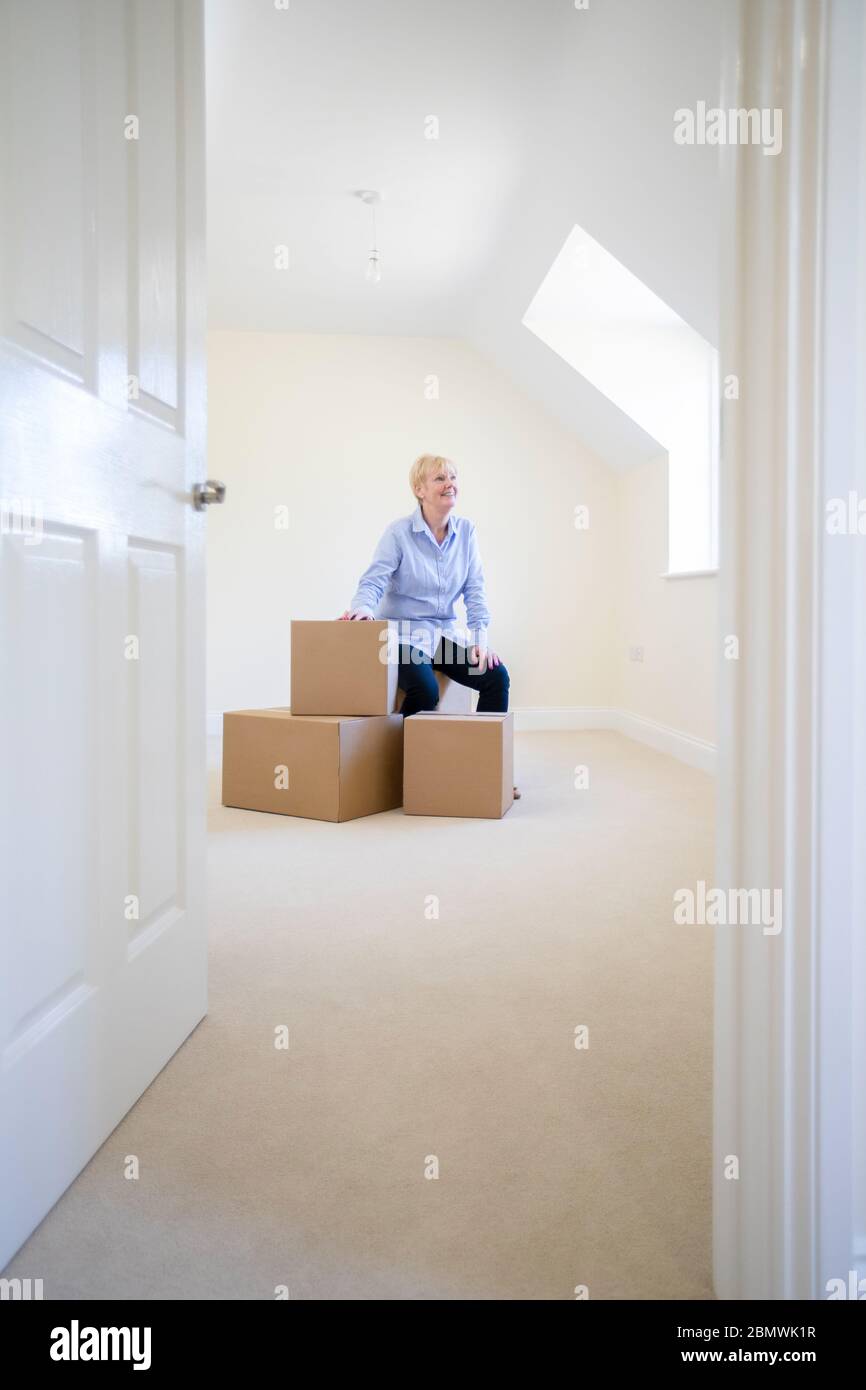 Seniorin Desizing In Ruhestand Sitzt Auf Boxen In New Home Am Beweglichen Tag Stockfoto