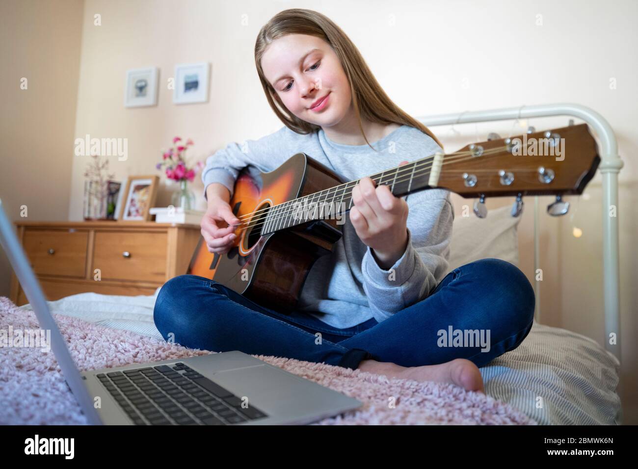 Teenager Mädchen Lernen, Acosutic Gitarre Mit Online-Lektion Auf Laptop-Computer Zu Spielen Stockfoto