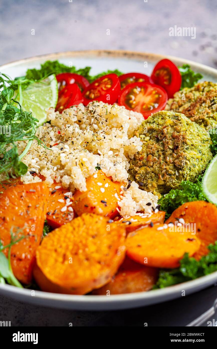 Veganes Abendessen. Quinoa-Salat mit gebackenen Süßkartoffeln, Falafel, Grünkohl und Erbsenpflanzen. Gesunde vegetarische buddha-Schüssel. Salatschüssel Falafel. Stockfoto