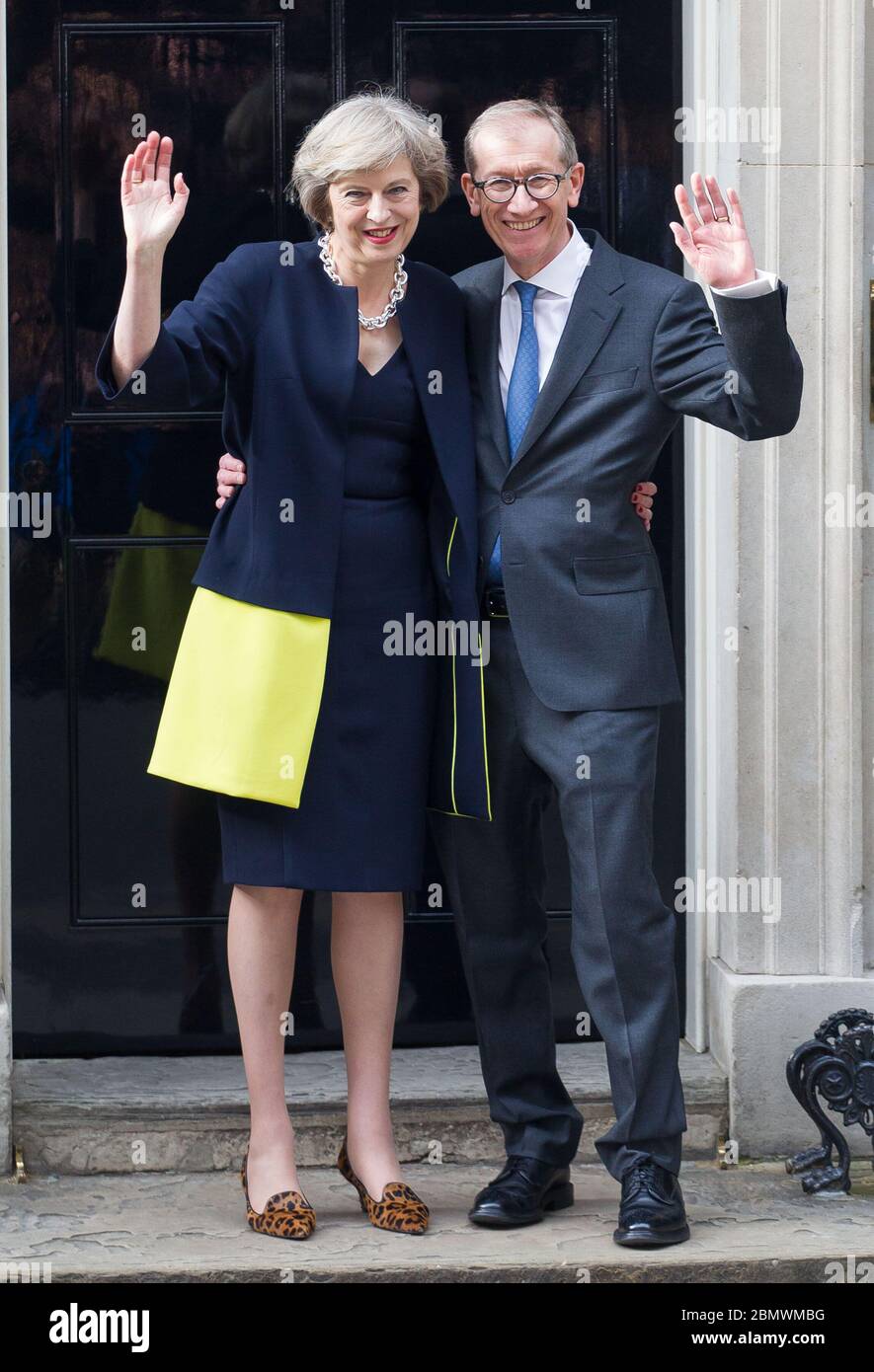 Premierministerin Theresa May und ihr Mann Philip winkt an ihrem ersten Arbeitstag für die zusammengebauten Kameras außerhalb der Downing Street 10. 13. J Stockfoto