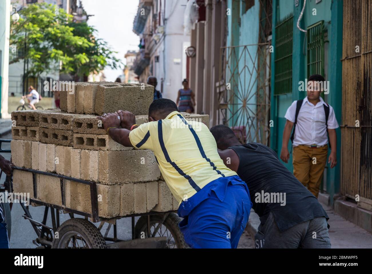 Menschen schieben einen mit Baumaterial beladenen Fahrradkarren, Havana Centro, Havanna, Kuba Stockfoto