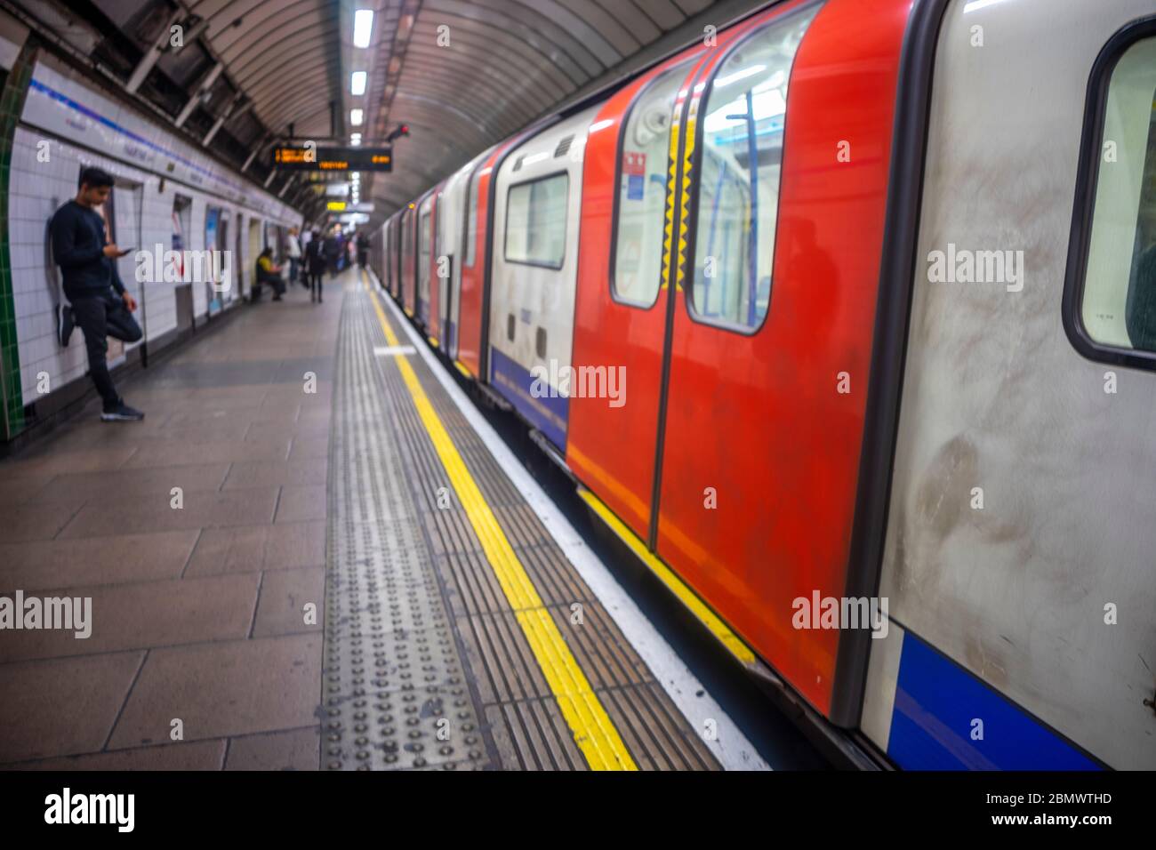 Verschwommene Londoner U-Bahn mit einigen Pendlern, die auf den nächsten Zug, London, Großbritannien warten Stockfoto