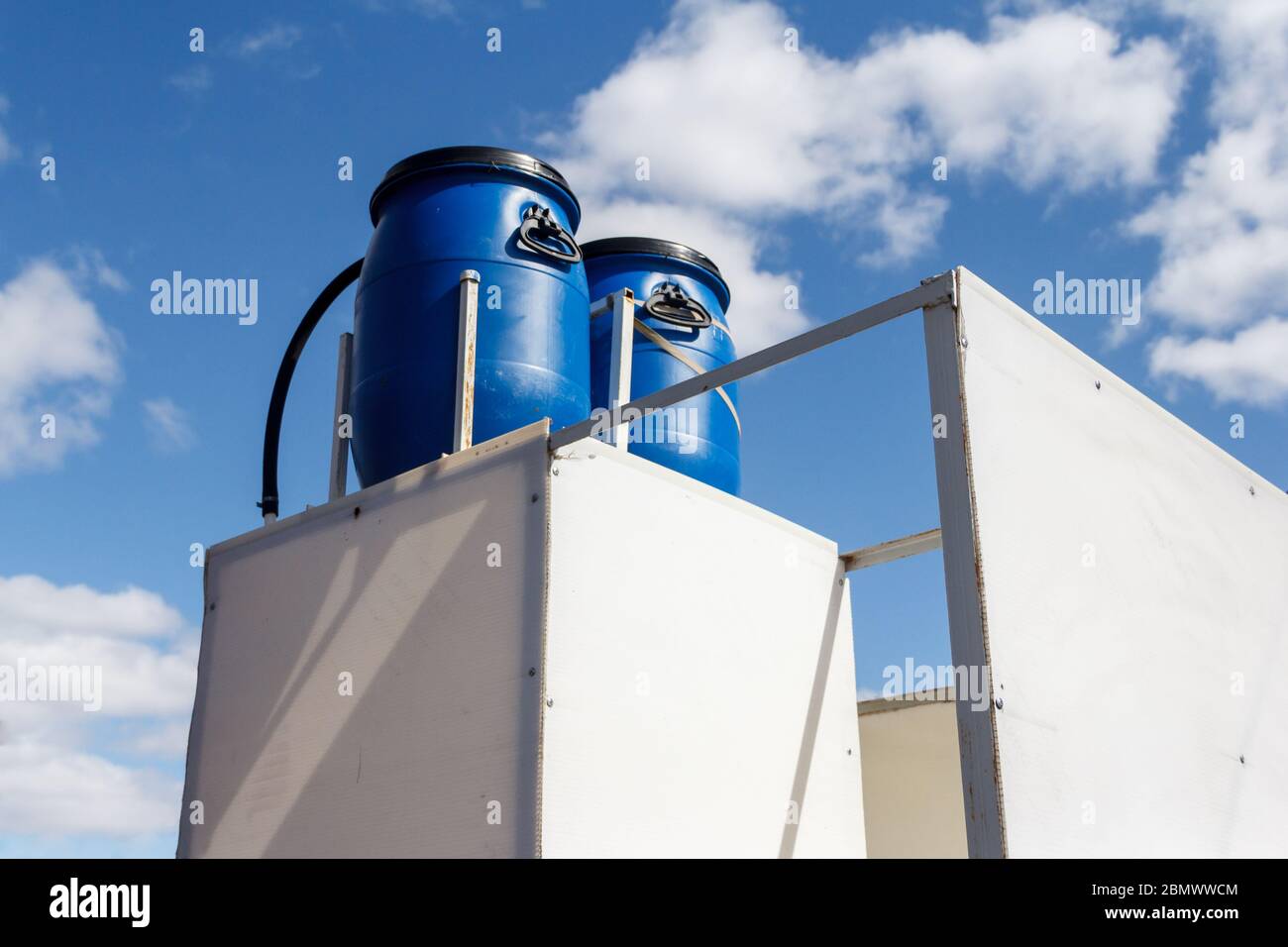 Zwei Kunststofffässer als Wasserspeicher in einer Landdusche. Stockfoto