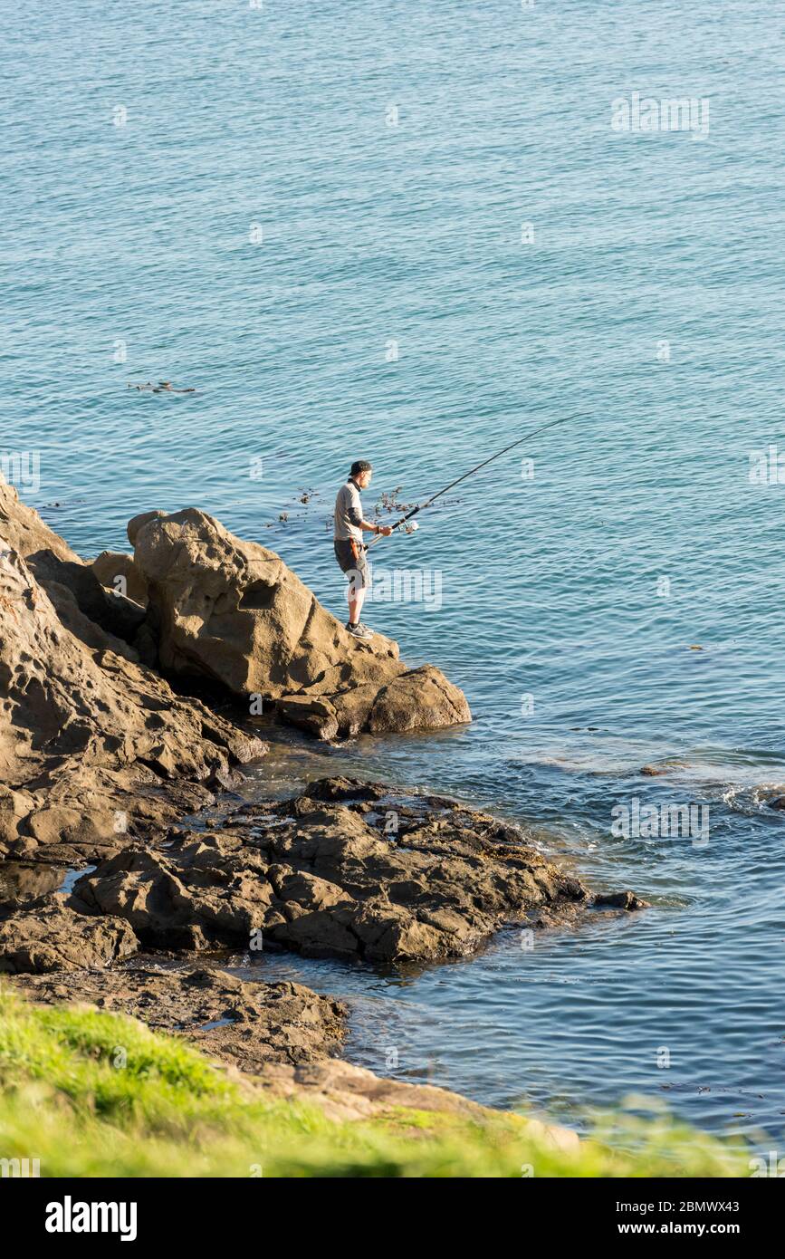 Ein Mann, der vor den Pöppeln im Südpazifik in der Nähe von Katiki Point Neuseeland fischt Stockfoto