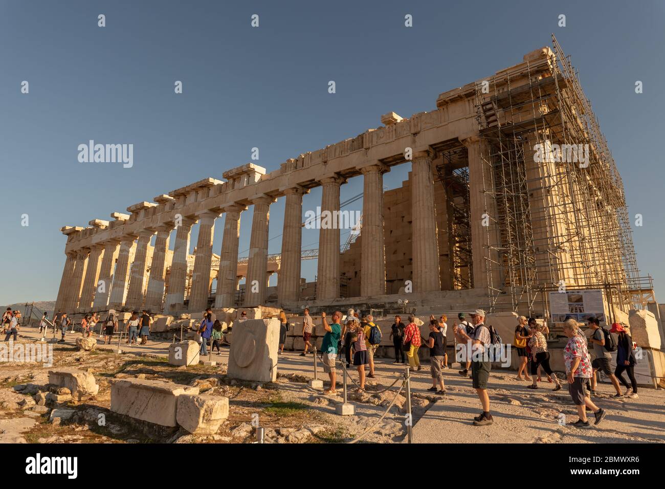 Ein Seitenansicht des parthenon mit Touristen im Vordergrund - Wandern, bewundern und fotografieren dieser antiken Ruine in Athen, Griechenland. Stockfoto