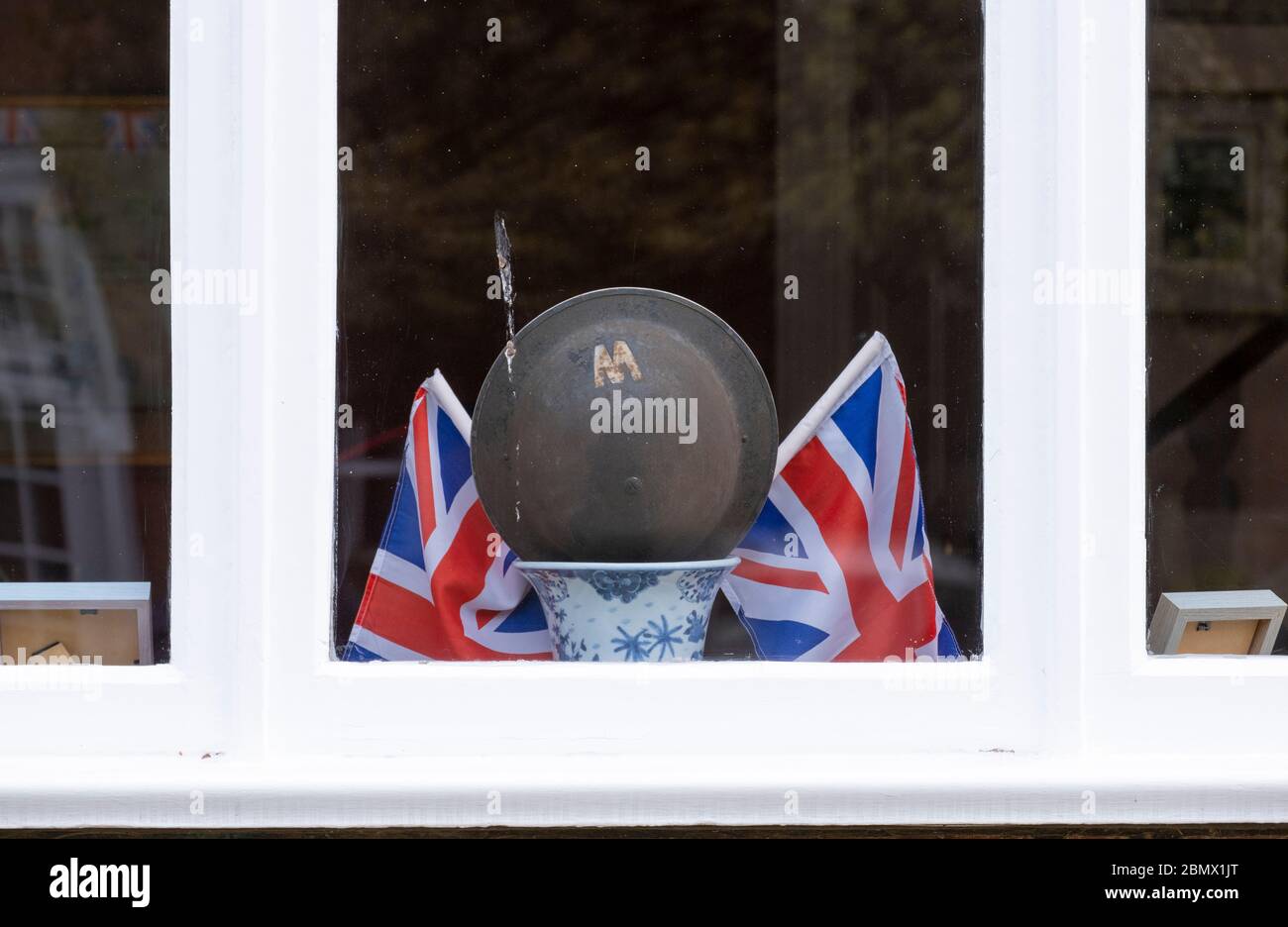 Wimbledon, London, Großbritannien. 11 Mai 2020. VE Day Gedenkdekorationen schmücken das Vorderfenster eines Hauses in Wimbledon Village einschließlich eines WW2 Air RAID Wächter Helm. Quelle: Malcolm Park/Alamy Live News. Stockfoto