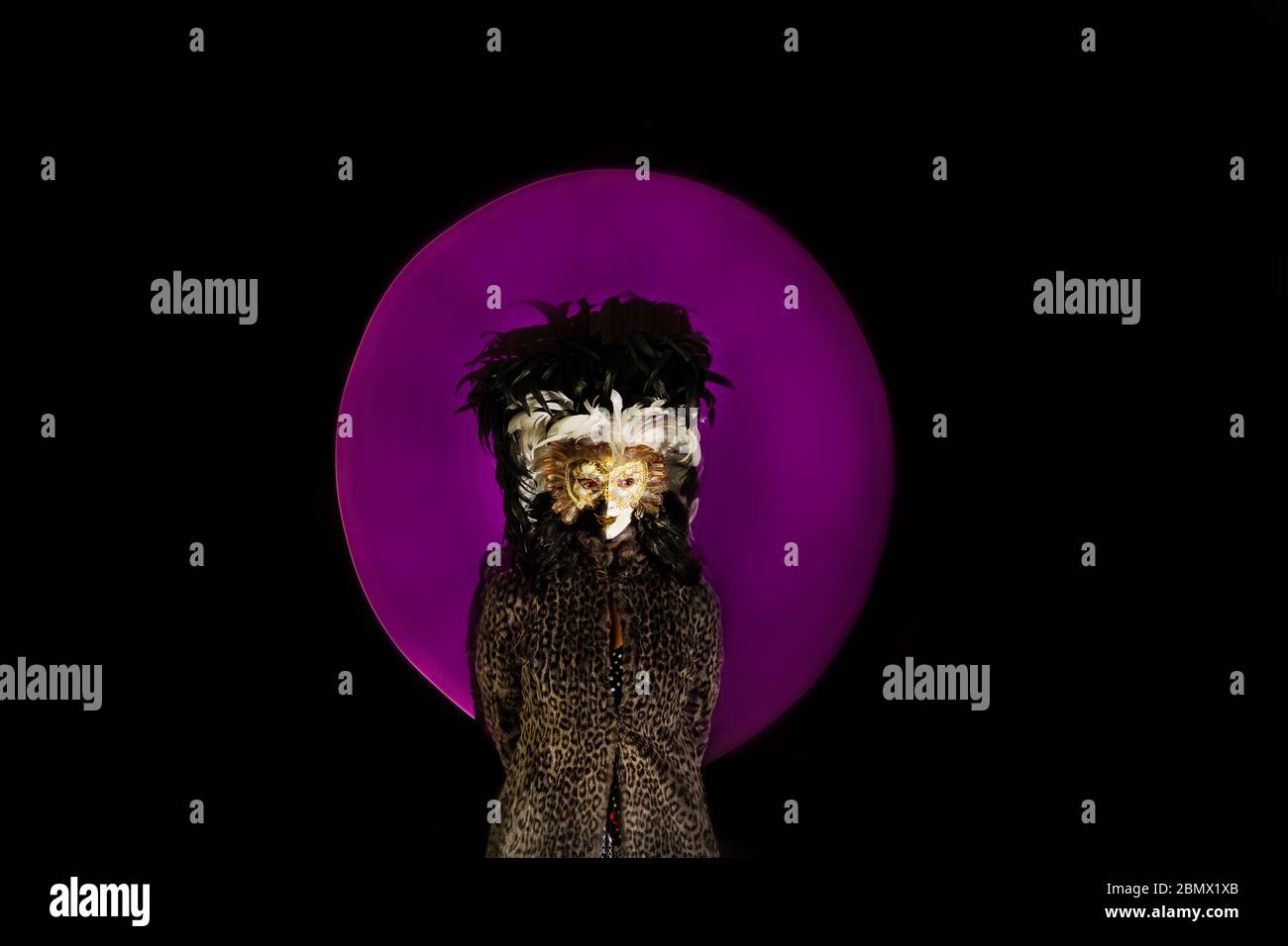 Frau im Pelzmantel und venezianische Maske mit Licht Lackierter Hintergrund Stockfoto
