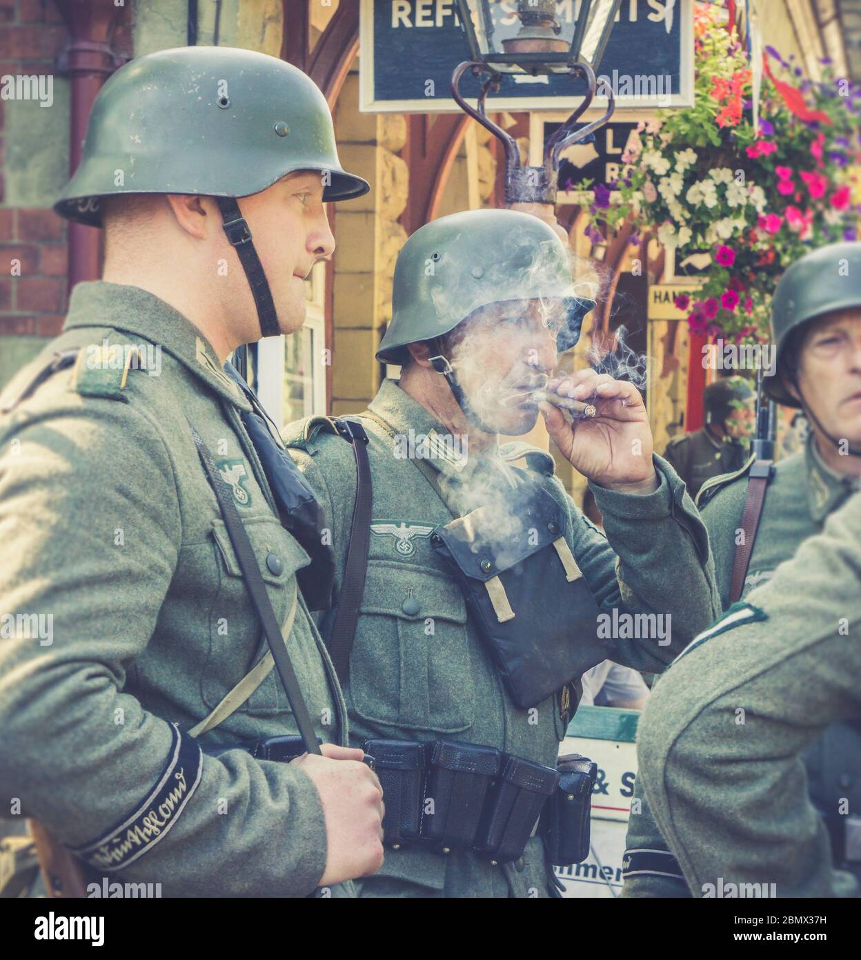 Retro-Ansicht von Nazi-Soldaten in Uniform Chat, Entspannung am Vintage-Bahnhof, Severn Valley Heritage Railway 1940s WW2 WWII war Zeit Sommer-Event. Stockfoto