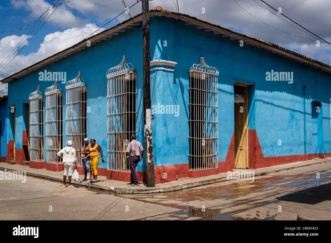 Menschen stehen an einer Straßenecke mit bunten Haus mit schmiedeeisernen Grill in der Kolonialzeit Zentrum der Stadt, Trinidad, Kuba Stockfoto