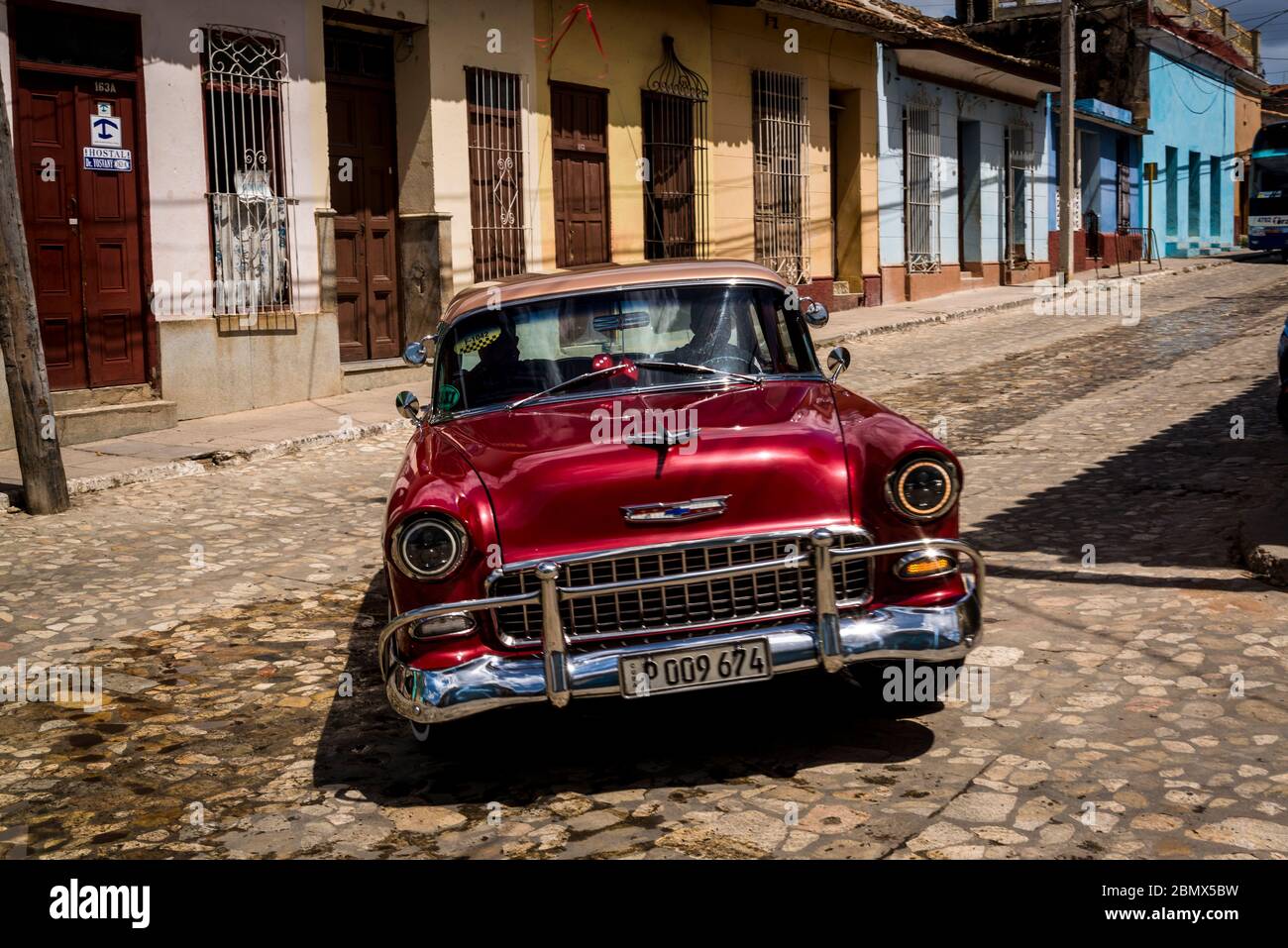 Oldtimer fahren eine typische Kopfsteinpflaster Straße mit bunten Häusern in der Kolonialzeit Zentrum der Stadt, Trinidad, Kuba Stockfoto