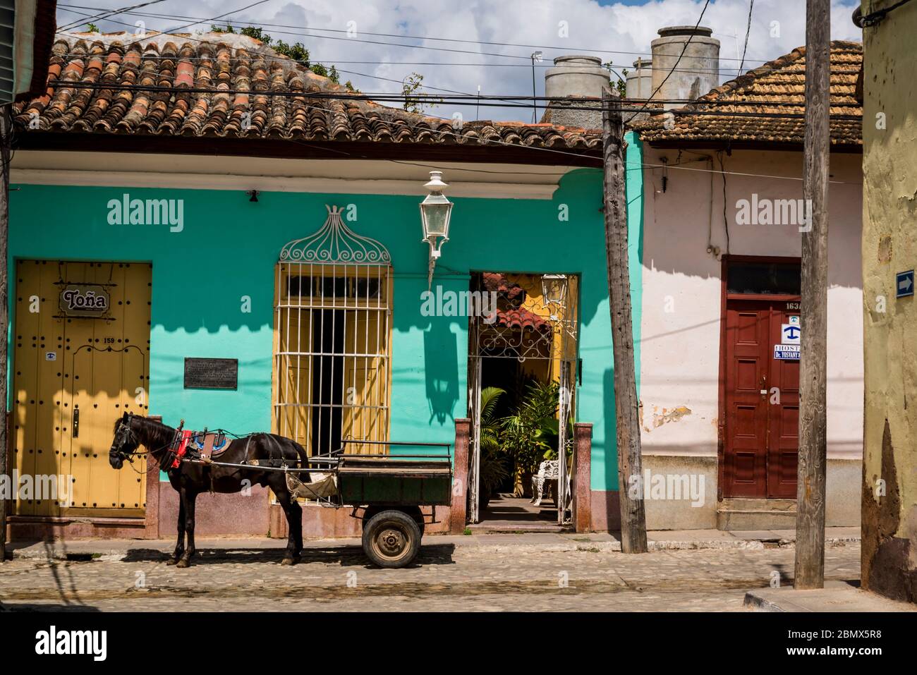 Pferd und Wagen vor einem Haus in einer typischen Kopfsteinpflaster Straße mit bunten Häusern im Kolonialzeitzentrum der Stadt, Trinidad, Kuba Stockfoto