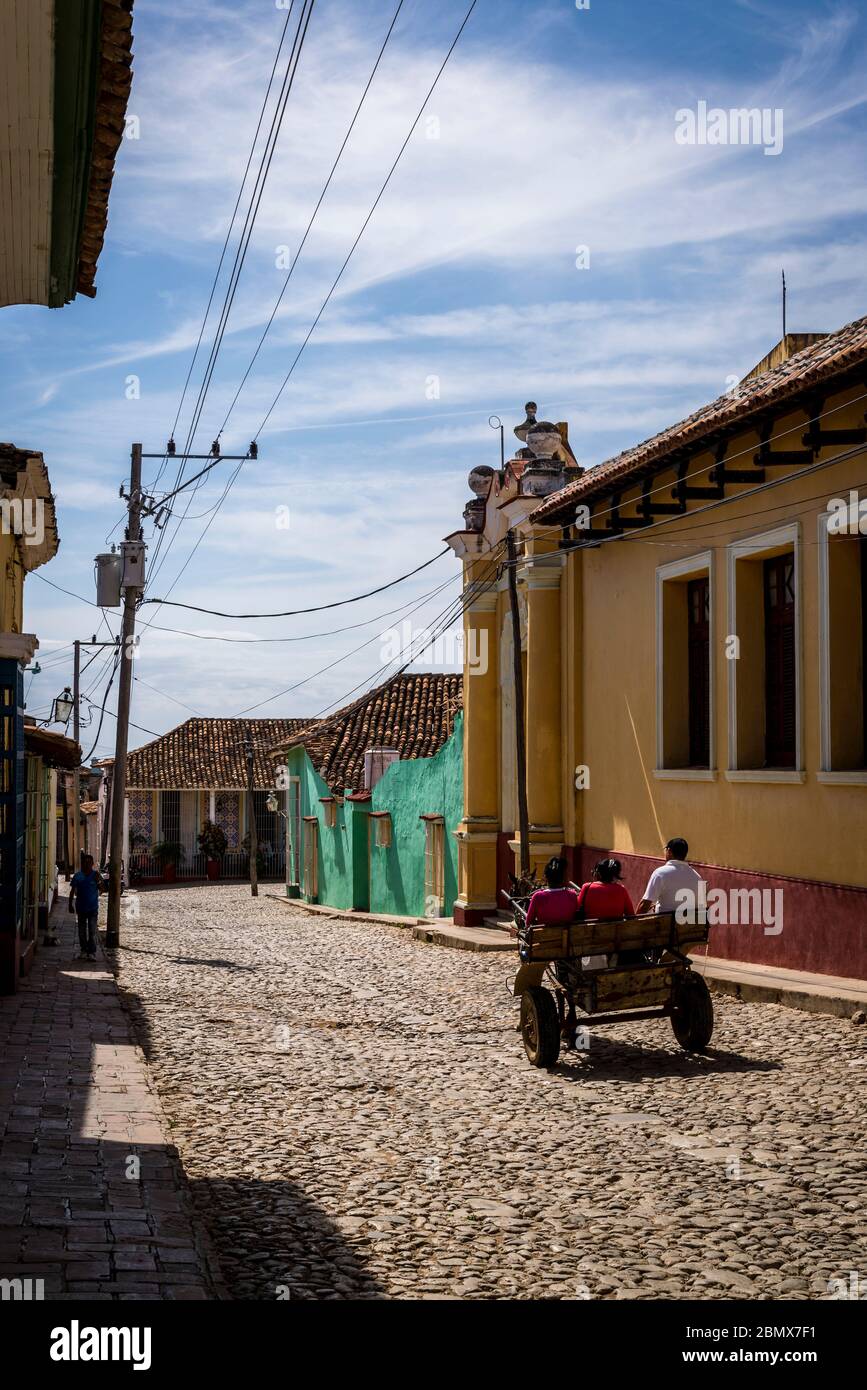 Mit dem Pferd und Wagen fahren Sie durch eine typische Kopfsteinpflaster-Straße mit bunten Häusern im Kolonialzeitzentrum der Stadt, Trinidad, Kuba Stockfoto