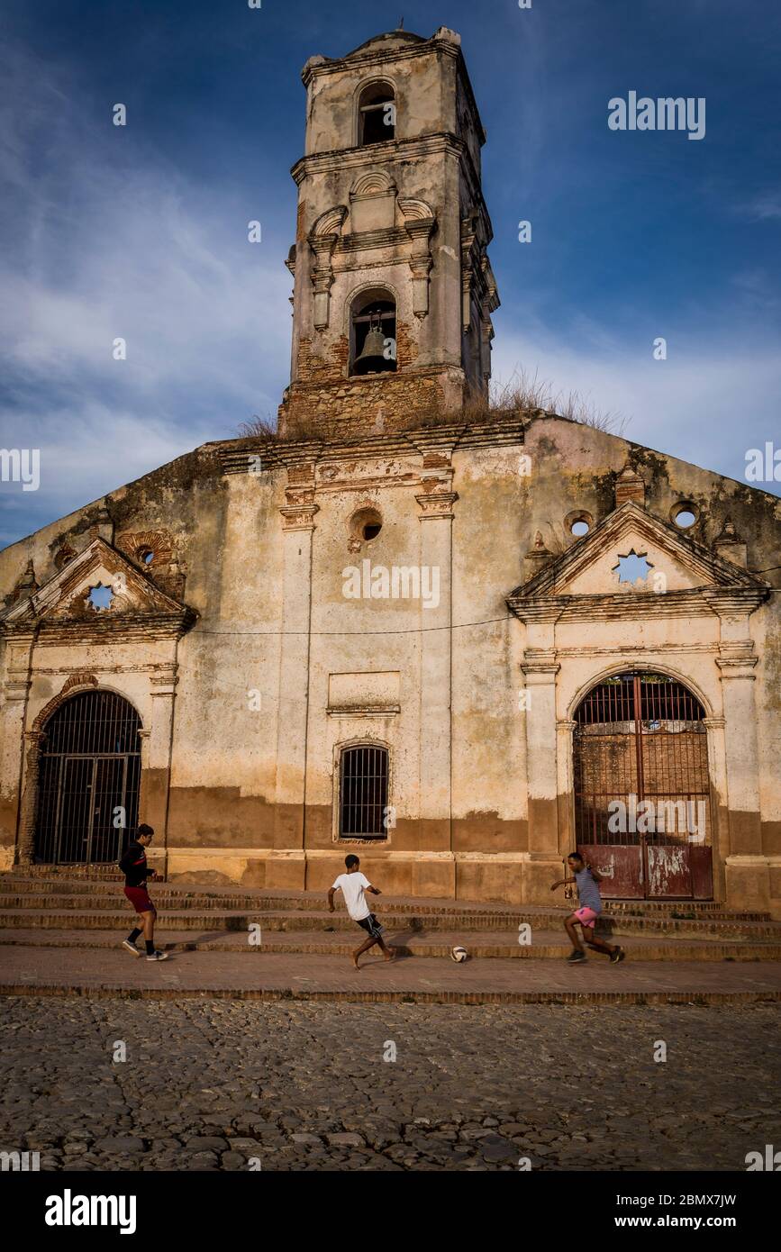 Kinder spielen Fußball vor dem verkommenen und schließen die Kirche von Saint Ana, Trinidad, Kuba Stockfoto