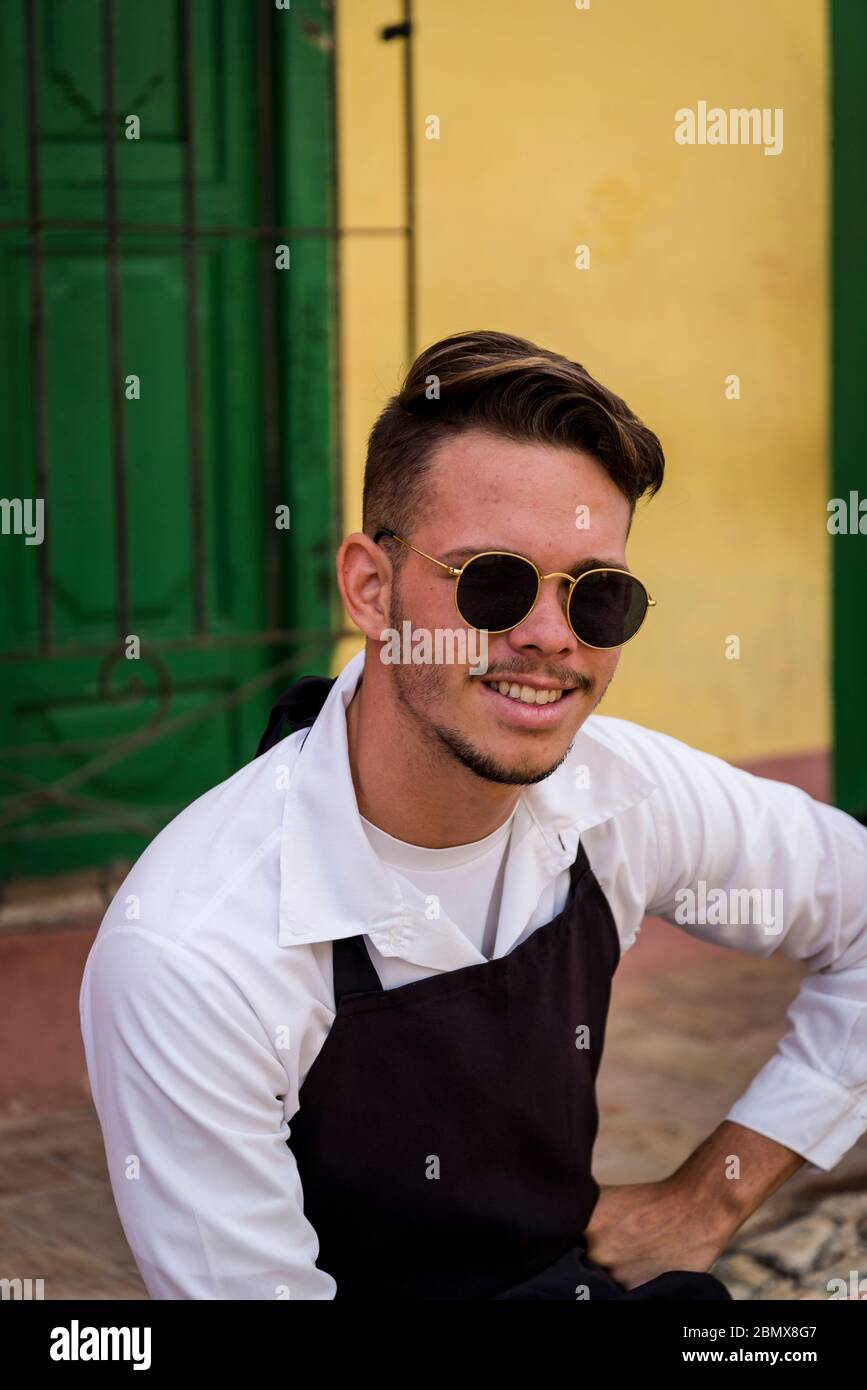 Junger Kellner sitzt vor dem Restaurant im Kolonialzeitzentrum der Stadt, Trinidad, Kuba Stockfoto