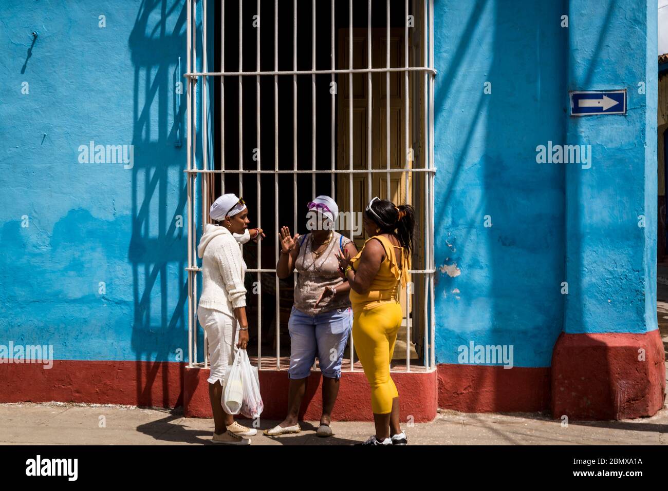Frauen sprechen vor einem bunten Haus mit schmiedeeisernem Grill im Zentrum der Kolonialzeit der Stadt, Trinidad, Kuba Stockfoto
