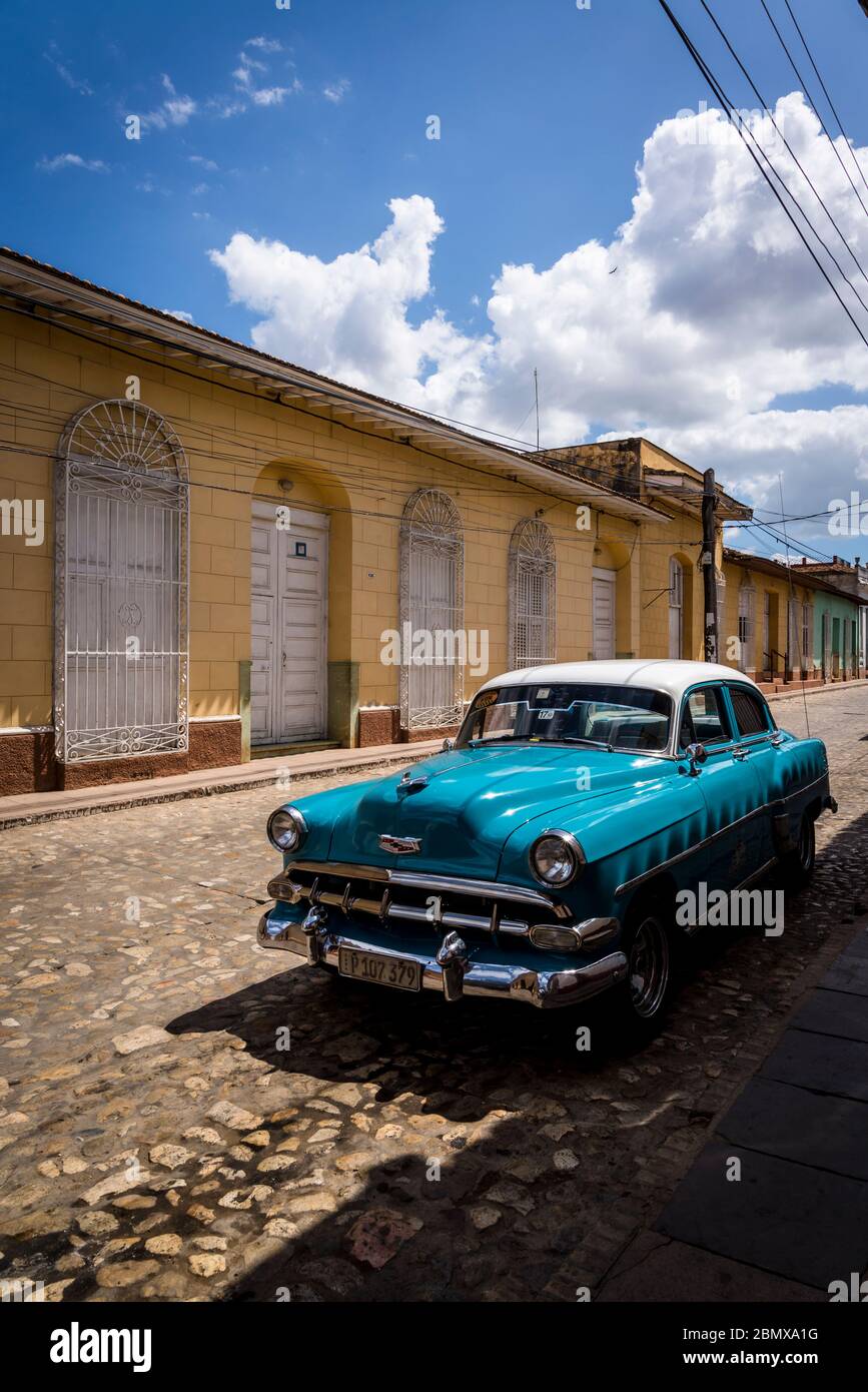 Oldtimer in einer typischen Kopfsteinpflaster Straße mit bunten Häusern in der Kolonialzeit Zentrum der Stadt, Trinidad, Kuba geparkt Stockfoto