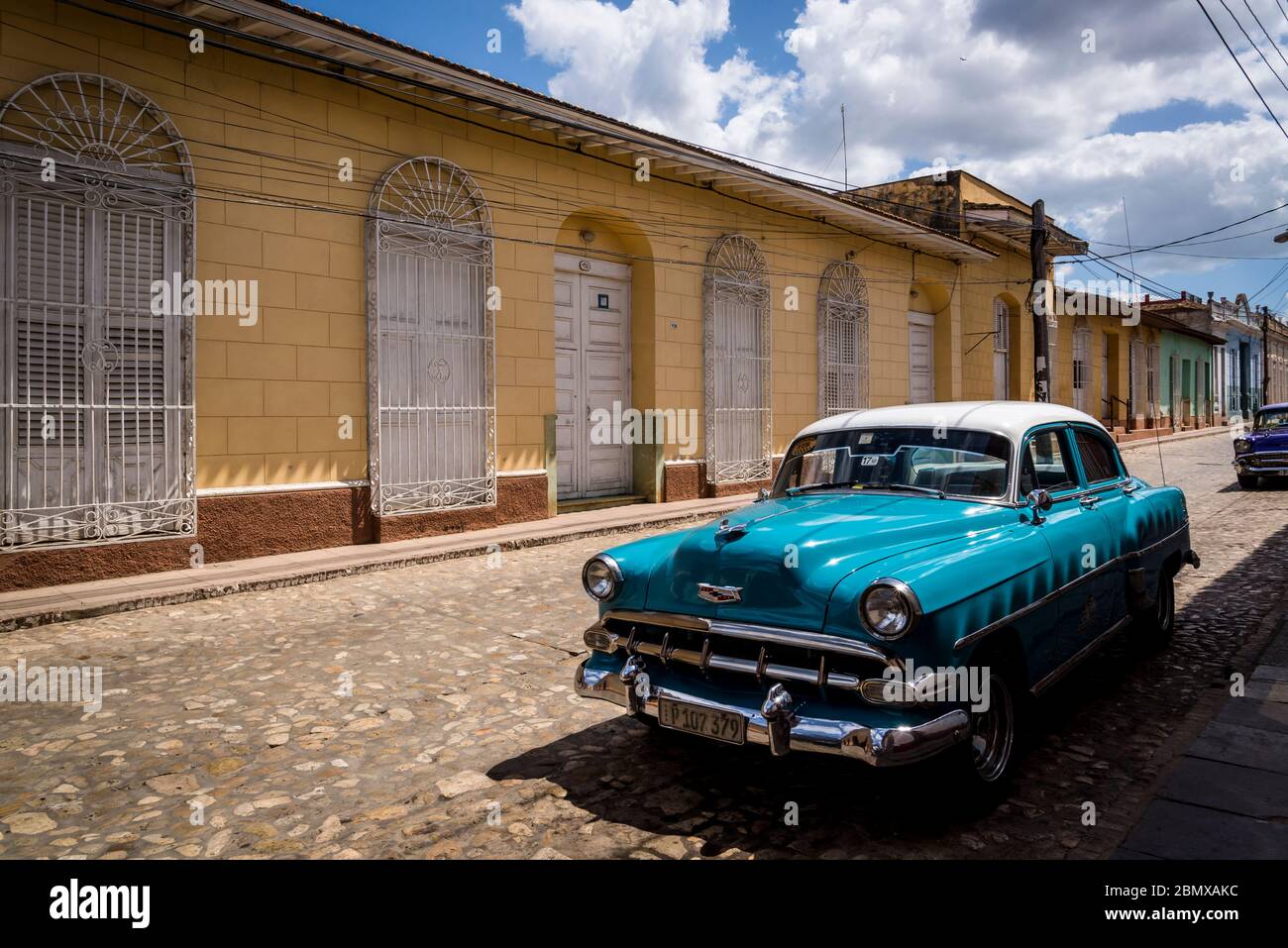 Oldtimer in einer typischen Kopfsteinpflaster Straße mit bunten Häusern in der Kolonialzeit Zentrum der Stadt, Trinidad, Kuba geparkt Stockfoto