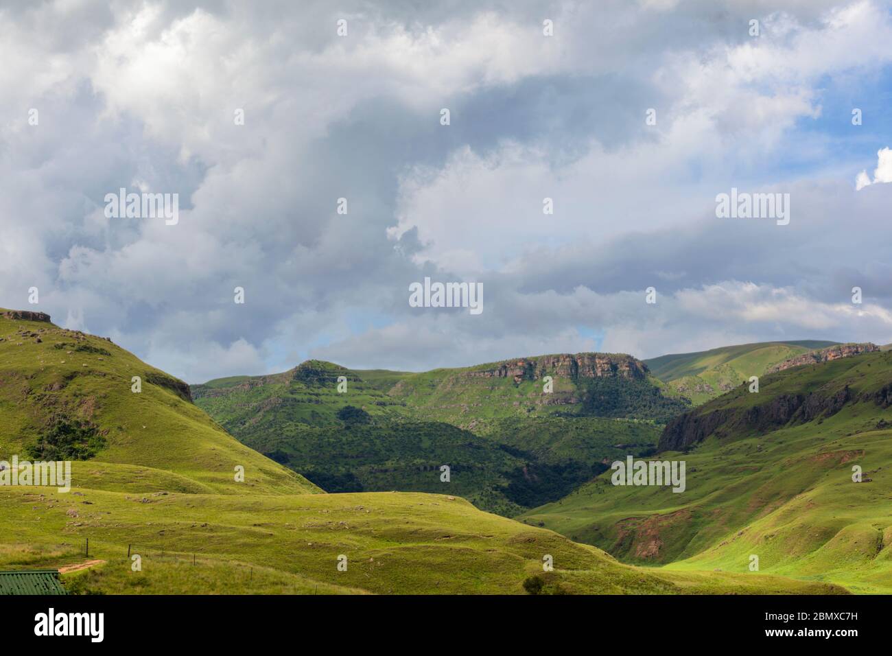 Blaue Wolken über grünen Bergen Stockfoto