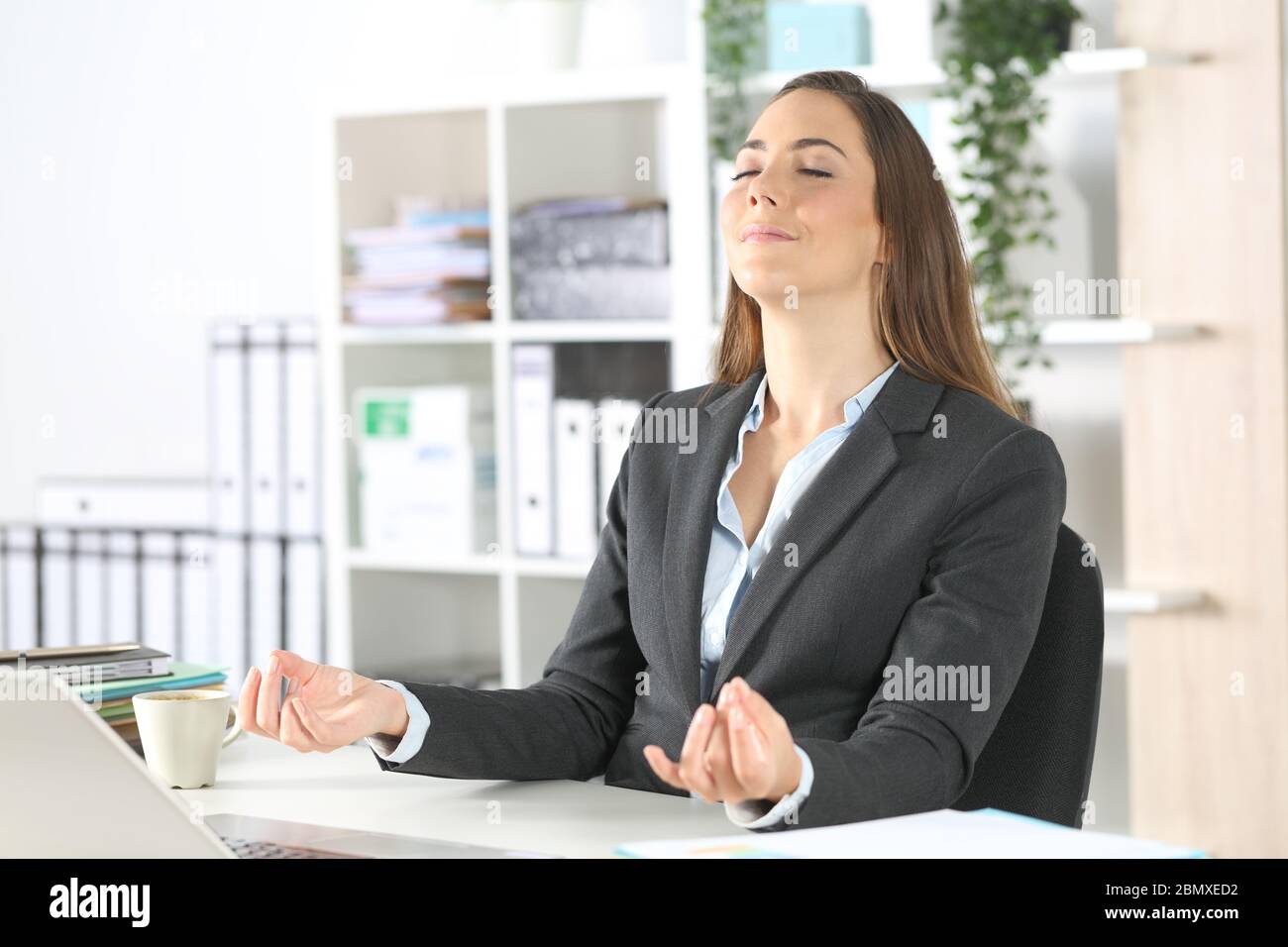 Executive Frau Stress Linderung tun Yoga auf ihrem Schreibtisch im Büro sitzen Stockfoto