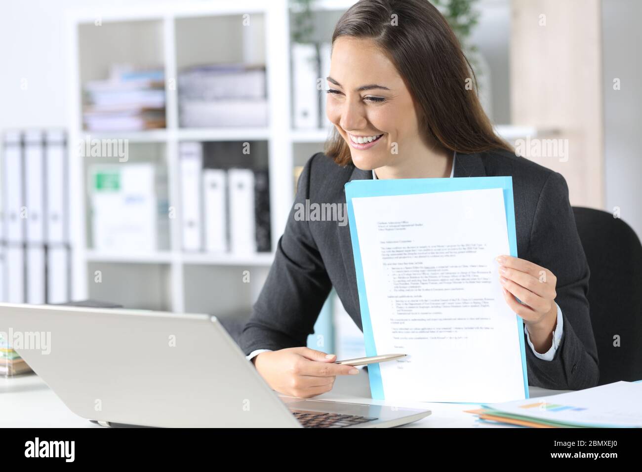 Glückliche Exekutive Frau zeigt Vertrag Unterschrift Raum auf Videocall auf Laptop sitzen auf ihrem Schreibtisch im Büro Stockfoto