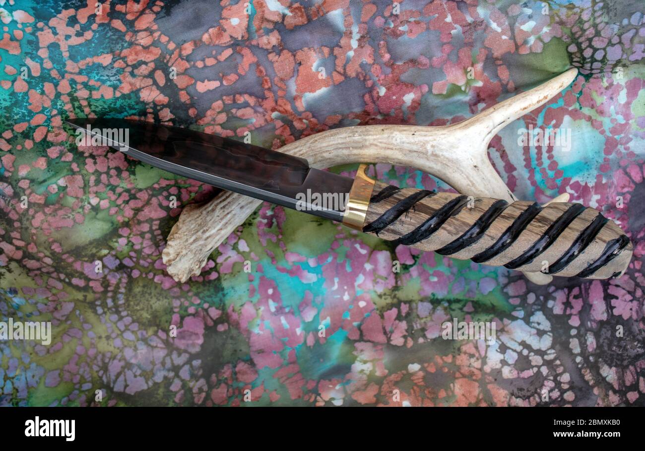 Ein einzigartiges bowie Messer mit Tropfenspitze und handgeschmiedeter damaskus-Klinge und Griff aus Myrtenholz mit dekorativen Rillen für sicheren Halt. Bokeh. Stockfoto