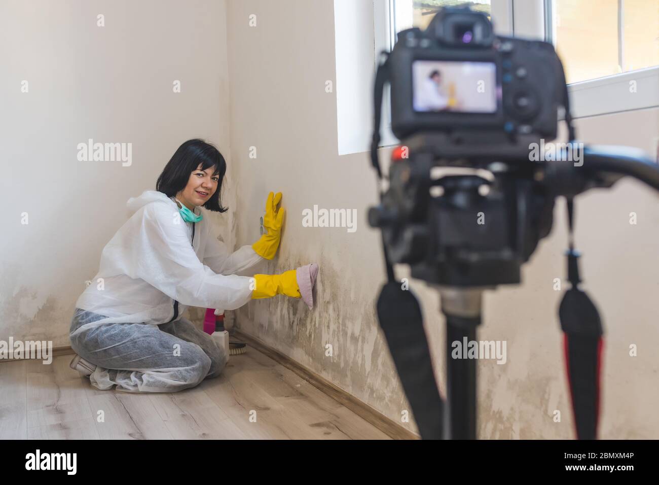 Video-Kamera Filmen, wie weibliche Arbeiter der Reinigung Service Entfernen von Schimmel von der Wand mit Sprühflasche mit Schimmel Sanierung Chemikalien, Schimmel Entfernung PR Stockfoto