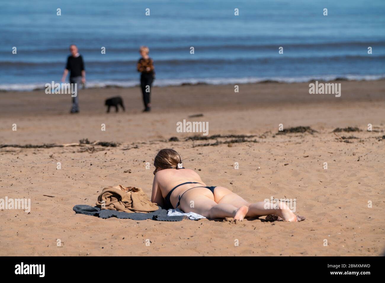 Portobello, Schottland, Großbritannien. 11 Mai 2020. Am späten Nachmittag Blick auf den beliebten Strand und die Promenade von Portobello. Trotz gelegentlicher Polizeikontrollen war die Öffentlichkeit entschlossen, sich zu entspannen und in der Sonne zu sitzen. Junge Frau in Bikini Sonnenbaden am Strand. Iain Masterton/Alamy Live News Stockfoto