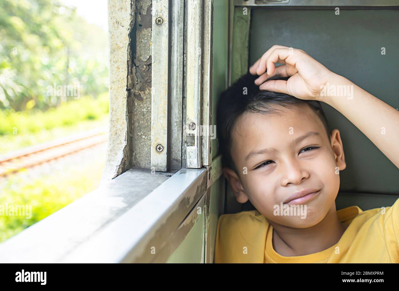 Portrait von asiatischen Jungen im Zug Hintergrund Fenster Aussicht und Bäumen. Stockfoto