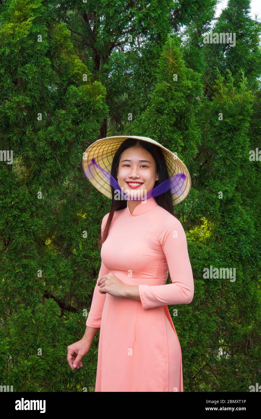Eine Vietnamesin in einem Ao Dai Kleid im Eingang zu einem Tempel Stockfoto