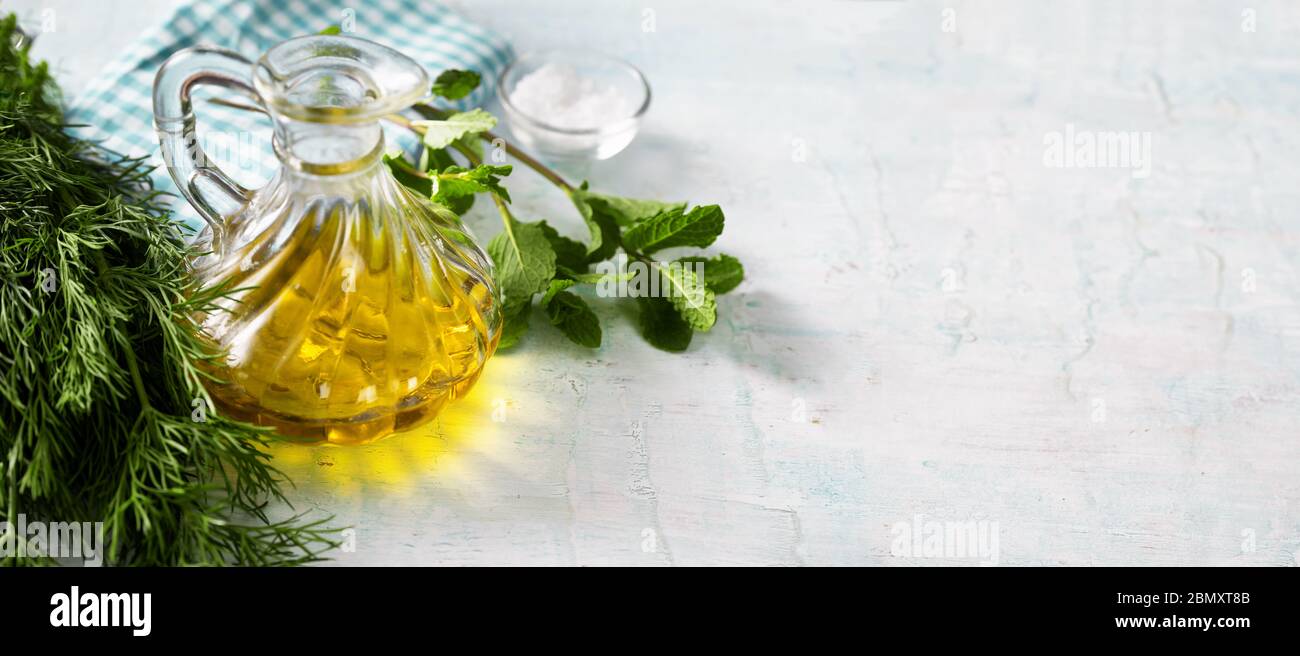 Flasche mit Olivenöl, Kräutern und Salz auf hellblauem Hintergrund Stockfoto