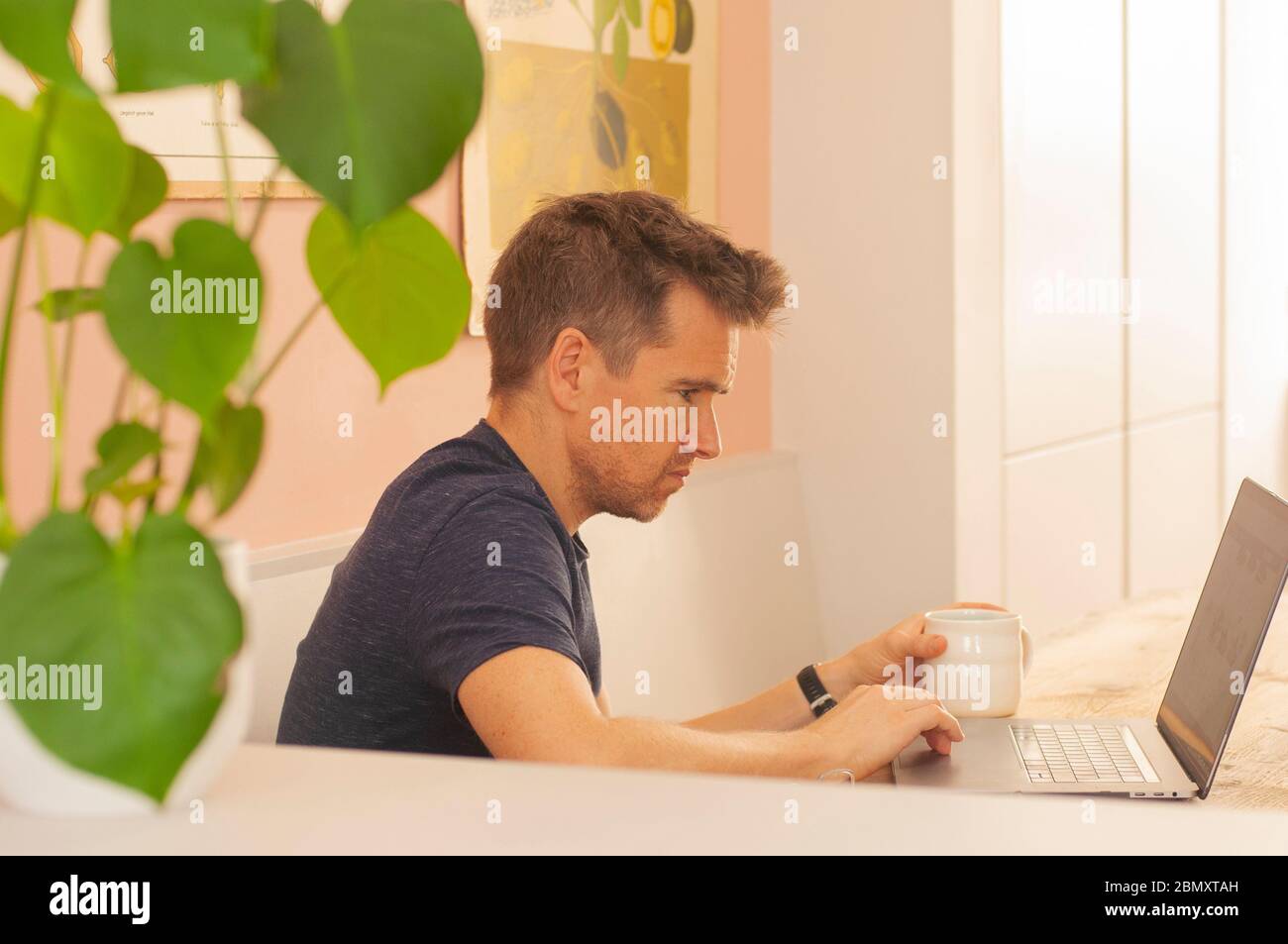 Porträt eines Mannes, der während der Sperrung des Coronavirus von zu Hause aus auf einem Laptop arbeitet. Querformat. Stockfoto