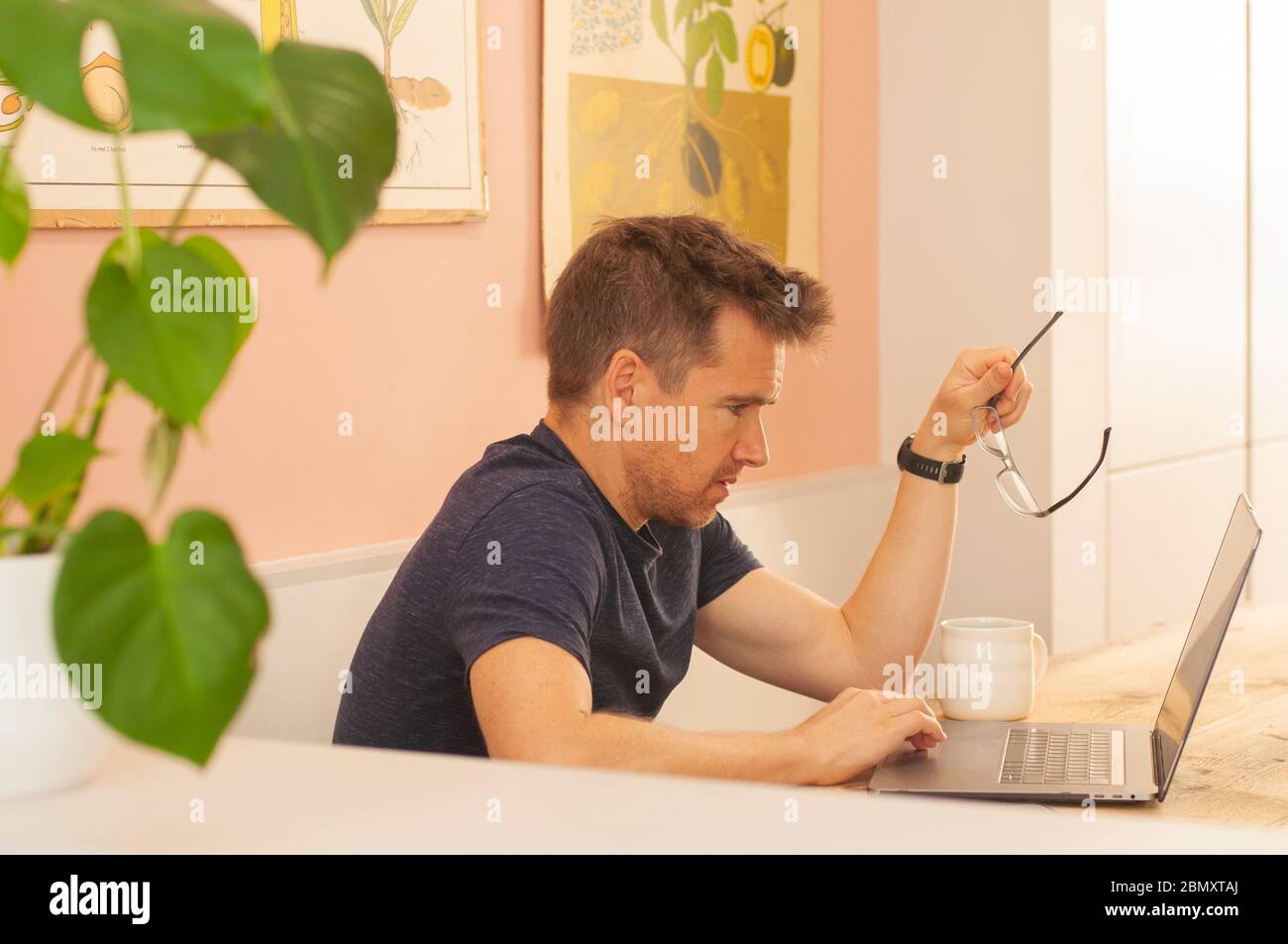 Porträt eines Mannes, der von zu Hause aus auf einem Laptop während des Coronavirus-Lockdowns mit Brille arbeitet. Querformat. Stockfoto