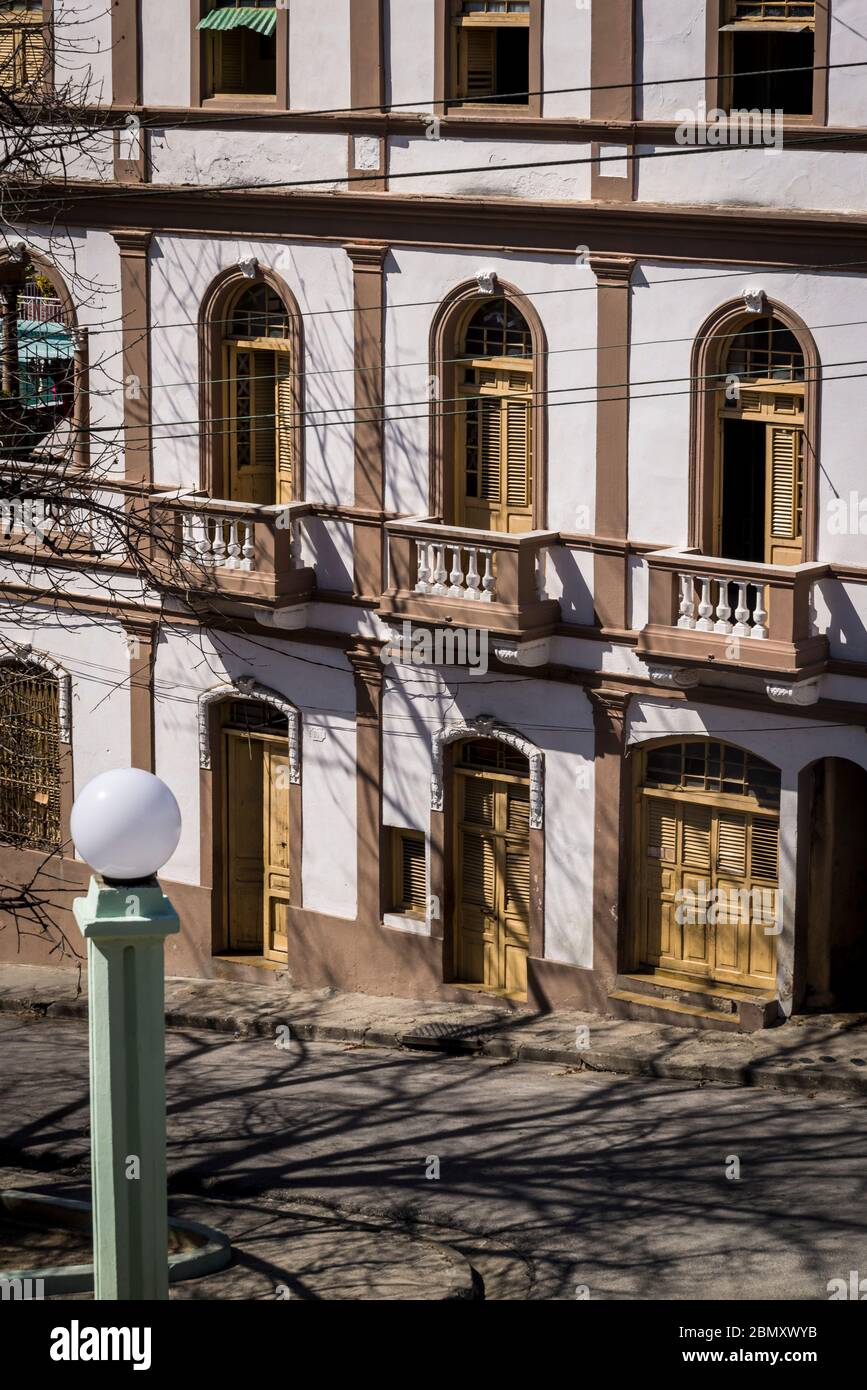 Stimmungsvolle Straße mit Gebäude im Kolonialstil und Baumschatten auf der Straße, Santiago de Cuba, Kuba Stockfoto