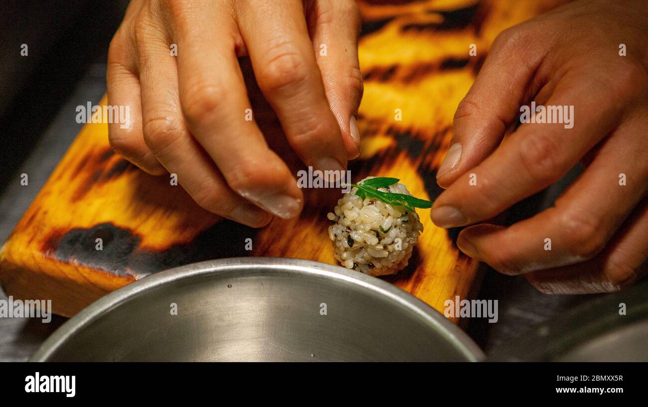 Ein Koch im Miya's Sushi in New Haven, CT, legt vorsichtig ein wild geerntes Kraut auf eine Reiskugel und andere Körner auf ein Holzbrett Stockfoto