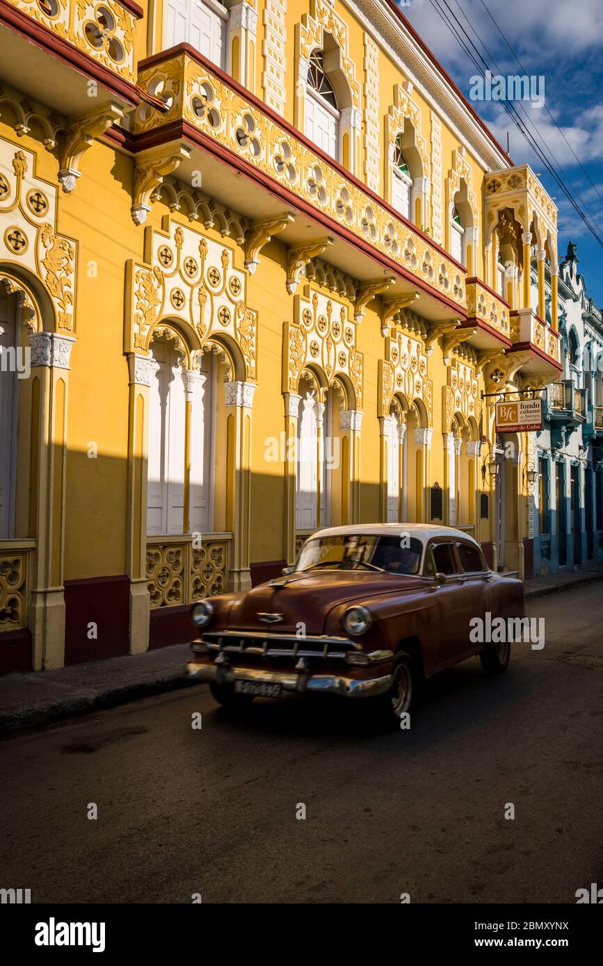 Oldtimer fahren in einer typischen Straße mit historischen Gebäuden im Stadtzentrum, Santiago de Cuba, Kuba Stockfoto