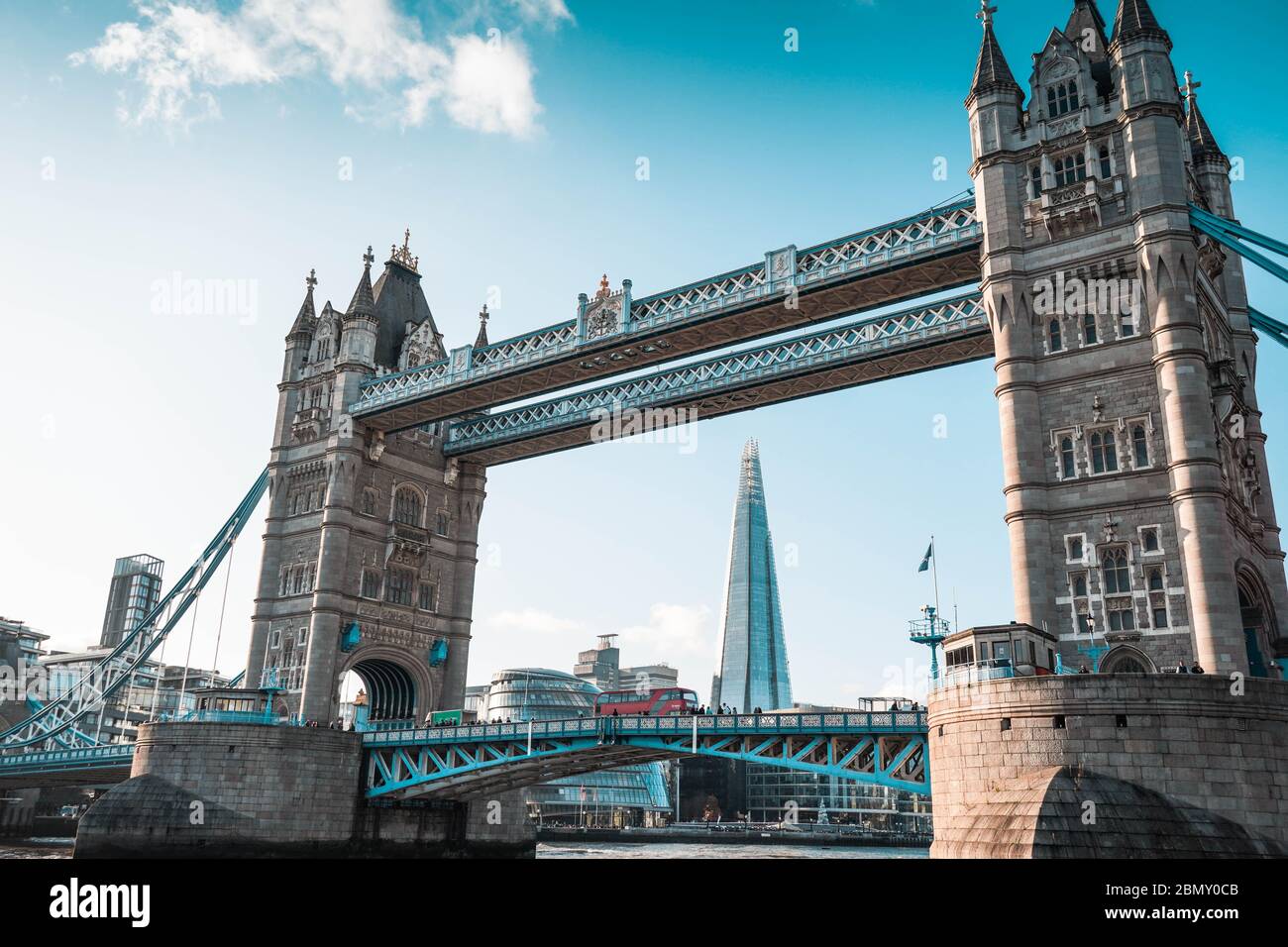 Ein Blick auf die Tower Bridge von der Themse aus. Die Shard, das Rathaus und ein Londoner Red Bus im Vorbeifahren Stockfoto