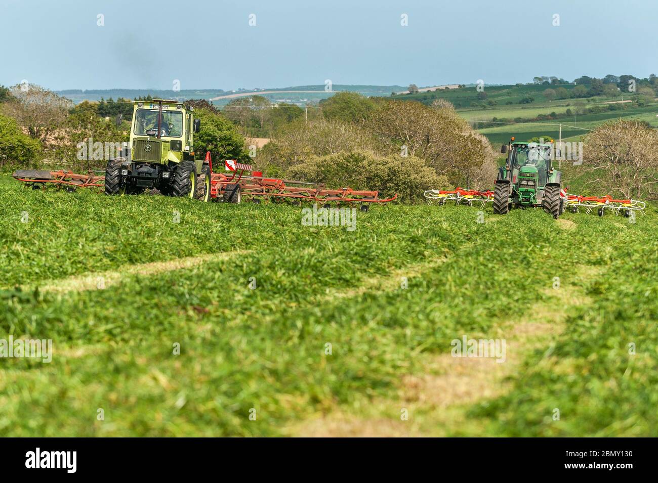 Timoleague, West Cork, Irland. Mai 2020. Ein MB Trak 900, angetrieben von David Deasy und John Deere 6620, angetrieben von Kevin Cahalane, mit einem SIP 1100 Tedder und Pottinger 900, lüften Gras für Silage auf der Farm von David Deasy von Timoleague. Das Gras wird morgen gerettet. Credit: AG News/Alamy Live News Stockfoto