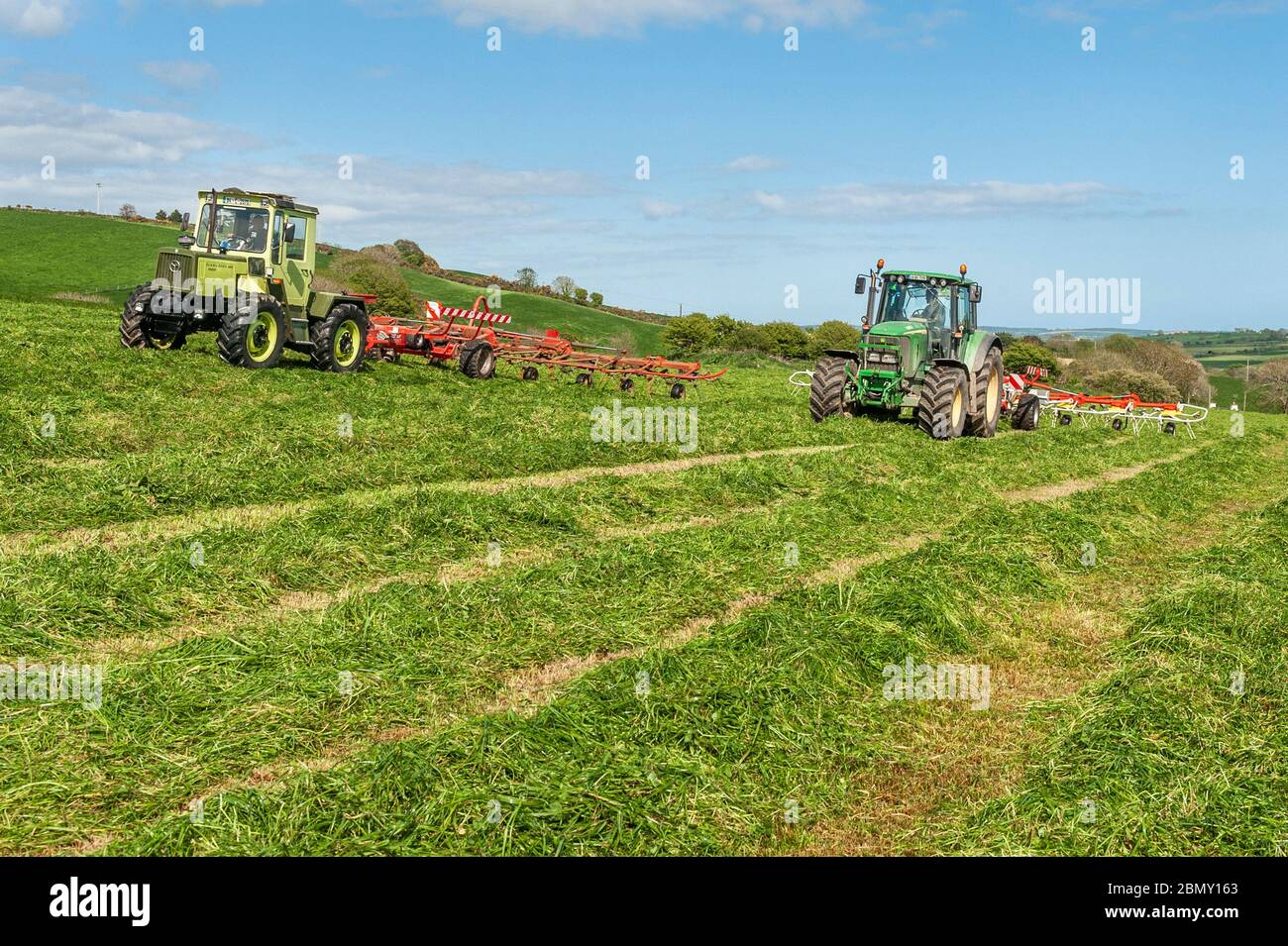 Timoleague, West Cork, Irland. Mai 2020. Ein MB Trak 900, angetrieben von David Deasy und John Deere 6620, angetrieben von Kevin Cahalane, mit einem SIP 1100 Tedder und Pottinger 900, lüften Gras für Silage auf der Farm von David Deasy von Timoleague. Das Gras wird morgen gerettet. Credit: AG News/Alamy Live News Stockfoto