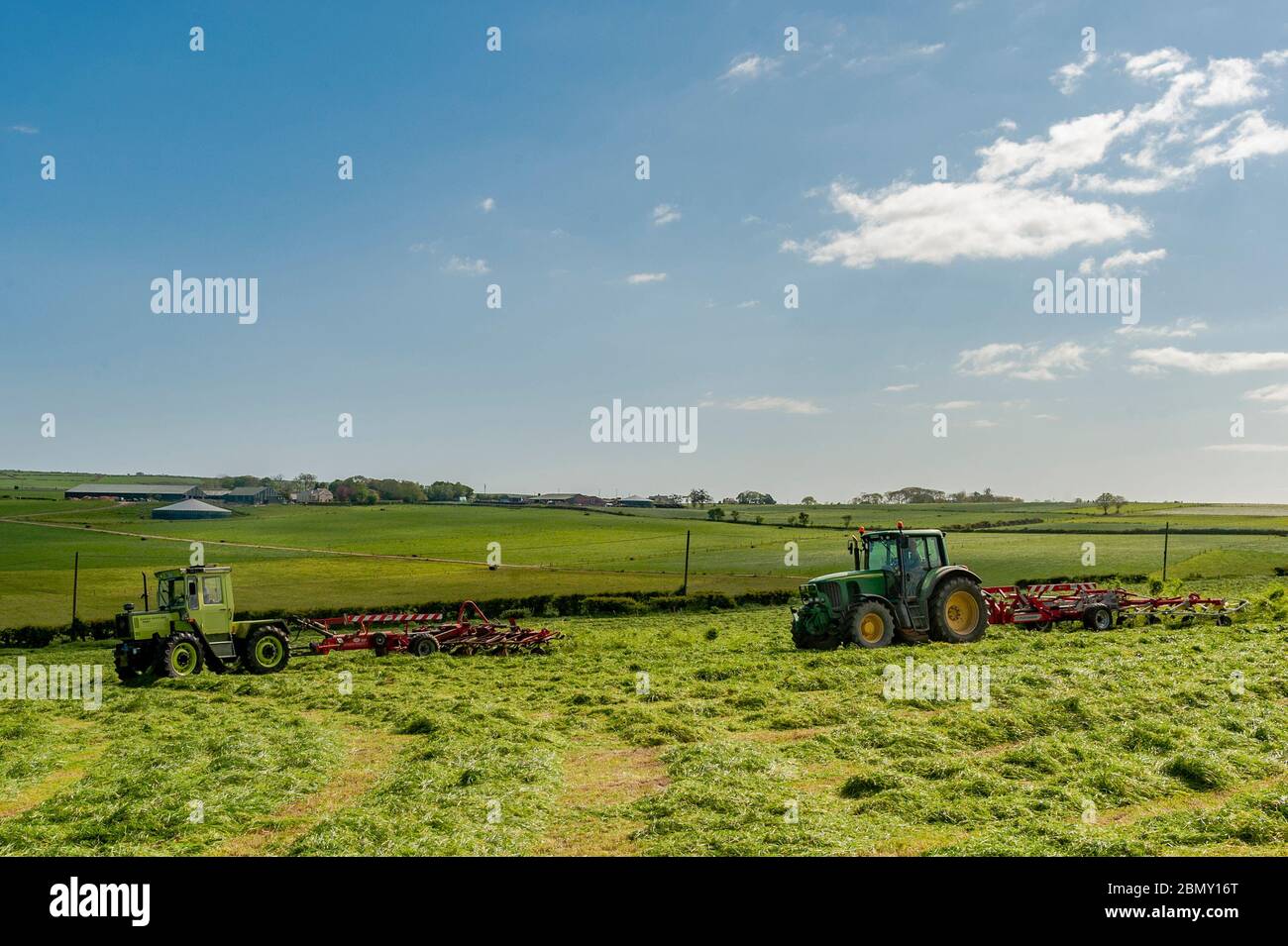 Timoleague, West Cork, Irland. Mai 2020. Ein MB Trak 900, angetrieben von David Deasy und John Deere 6620, angetrieben von Kevin Cahalane, mit einem SIP 1100 Tedder und Pottinger 900, lüften Gras für Silage auf der Farm von David Deasy von Timoleague. Das Gras wird morgen gerettet. Credit: AG News/Alamy Live News Stockfoto