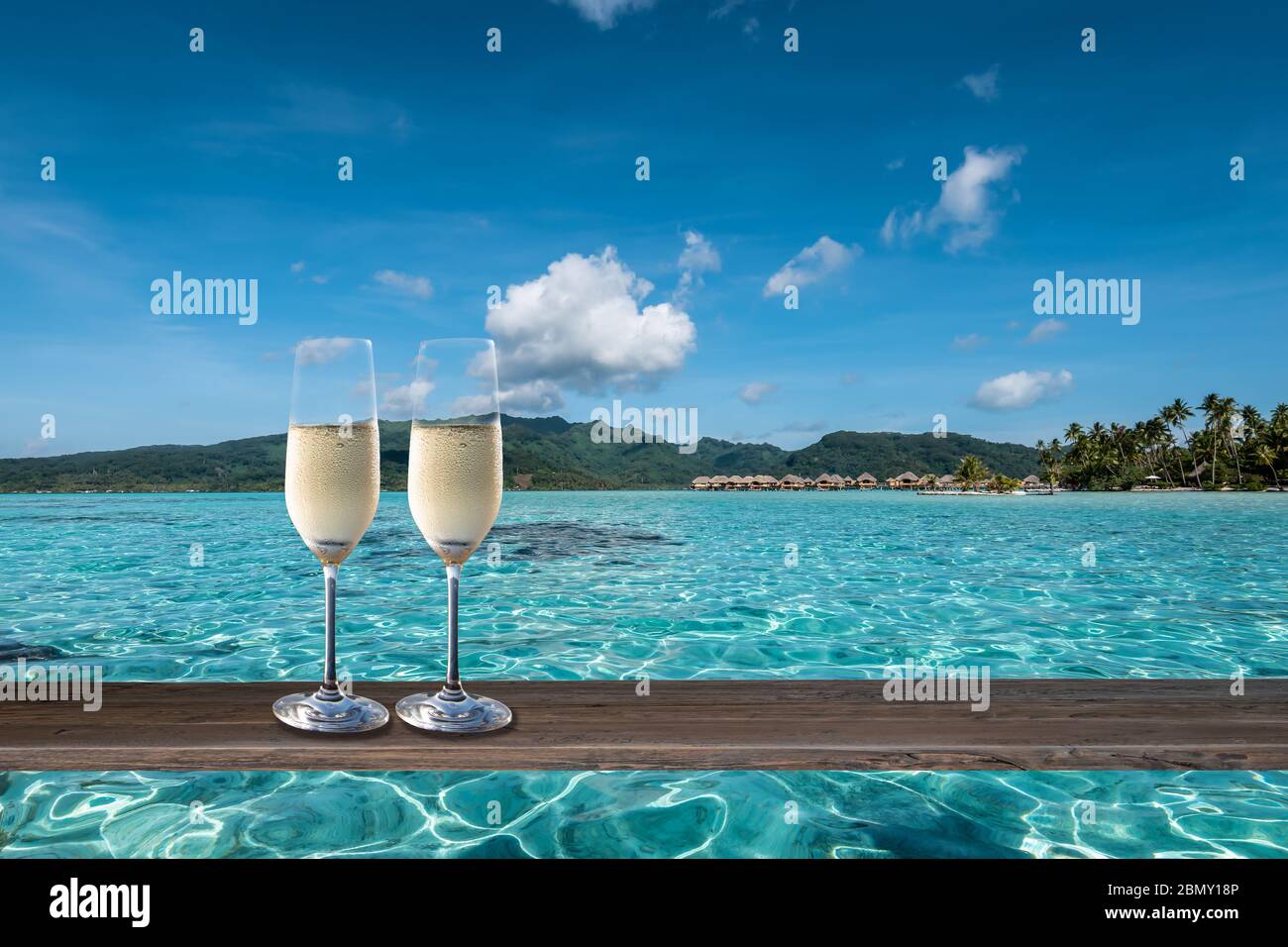Luxus-Sommerurlaub Feier mit zwei Gläsern Champagner auf einem Tisch in der Lagune der Society Islands. Stockfoto