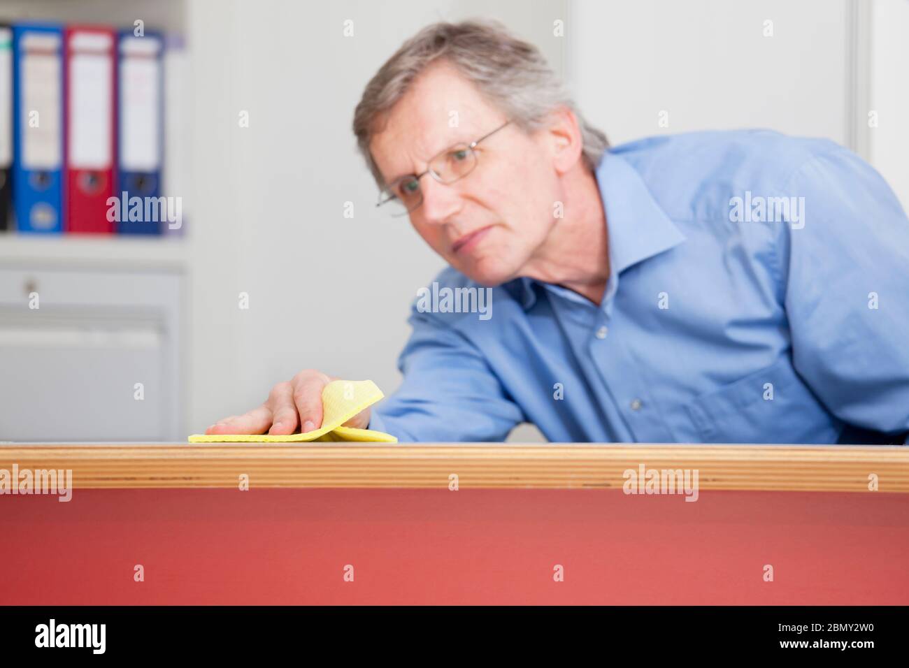 Reifer Geschäftsmann putzt einen Schreibtisch in einem Büro - konzentrieren Sie sich auf die Hand Stockfoto