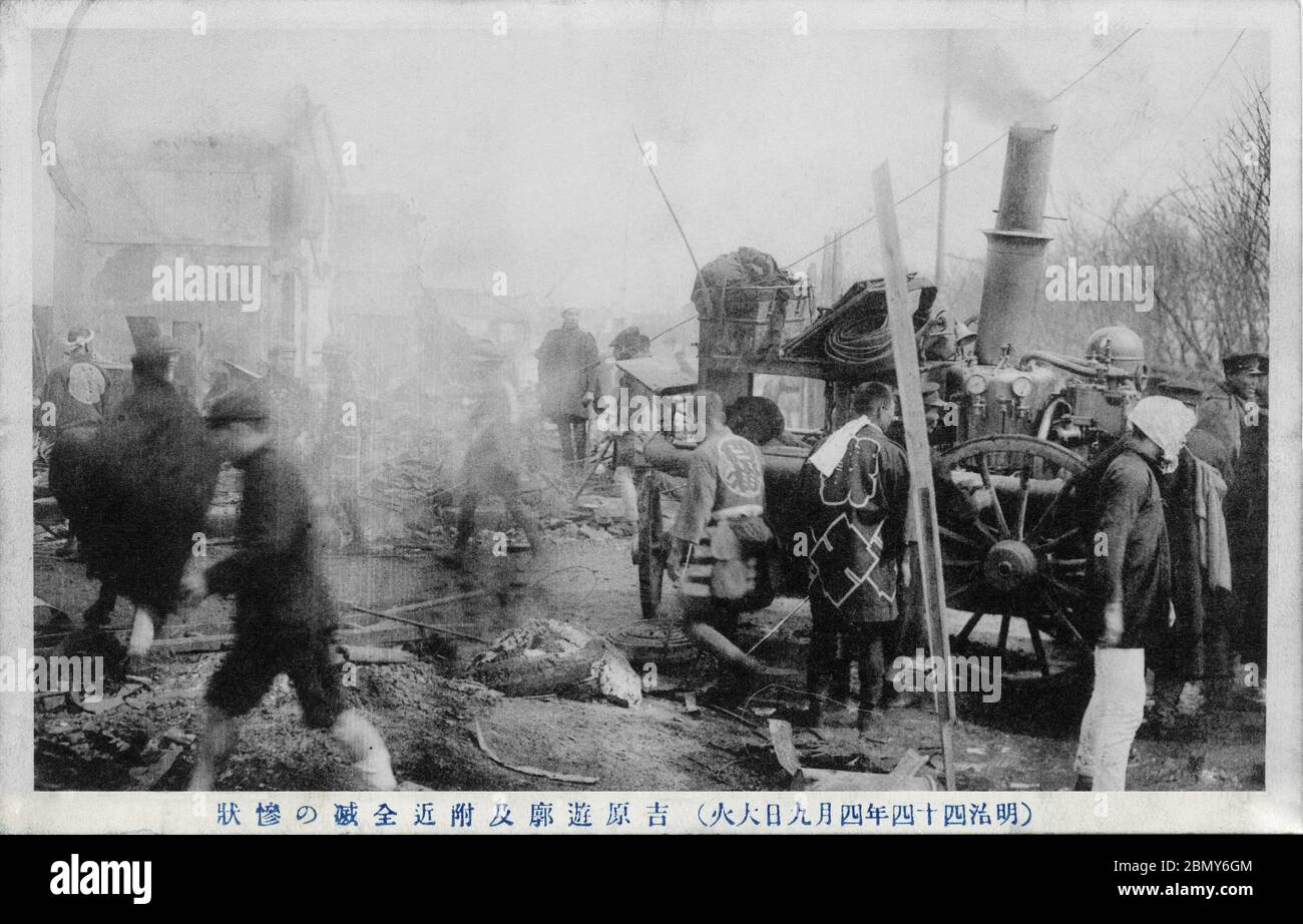 [ 1911 Japan - Feuer im Rotlichtviertel, Tokio ] - Feuerwehrleute, die eine noch seltene Dampffeuermaschine benutzen am Schauplatz des Shin-Yoshiwara Great Fire (新吉原大火, Shin-Yoshiwara Taika) vom 9. April 1911 (Meiji 44) im Prostitutionsbezirk Shin-Yoshiwara (auch Yoshiwara genannt) in Tokio. Originaltext:（明治四十四年四月九日大火）吉原遊郭乃付近全滅の惨状。 Vintage Postkarte des 20. Jahrhunderts. Stockfoto