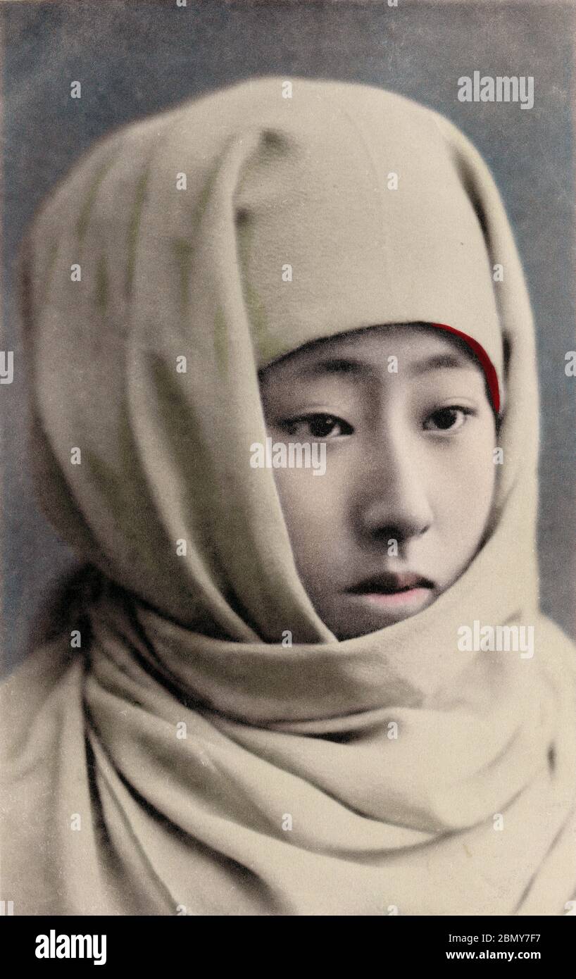 [ 1900er Japan - Frau mit Okozukin-Kapuze ] - EINE Frau hat einen Okozukin (御高祖頭巾) um ihren Kopf gewickelt, um sich vor der Winterkälte zu schützen. Diese Postkarte wurde zwischen Oktober 1900 (Meiji 33) und März 1907 (Meiji 40) veröffentlicht. Vintage-Postkarte des 20. Jahrhunderts. Stockfoto