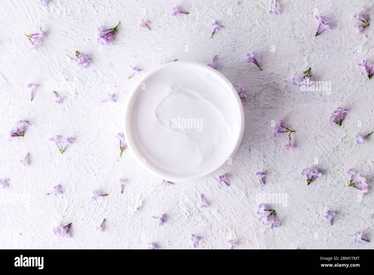 Weiße kosmetische Creme mit Blumen. Feuchtigkeitsspendende Creme für die Hautpflege. Gesundheit und Schönheit. Stockfoto