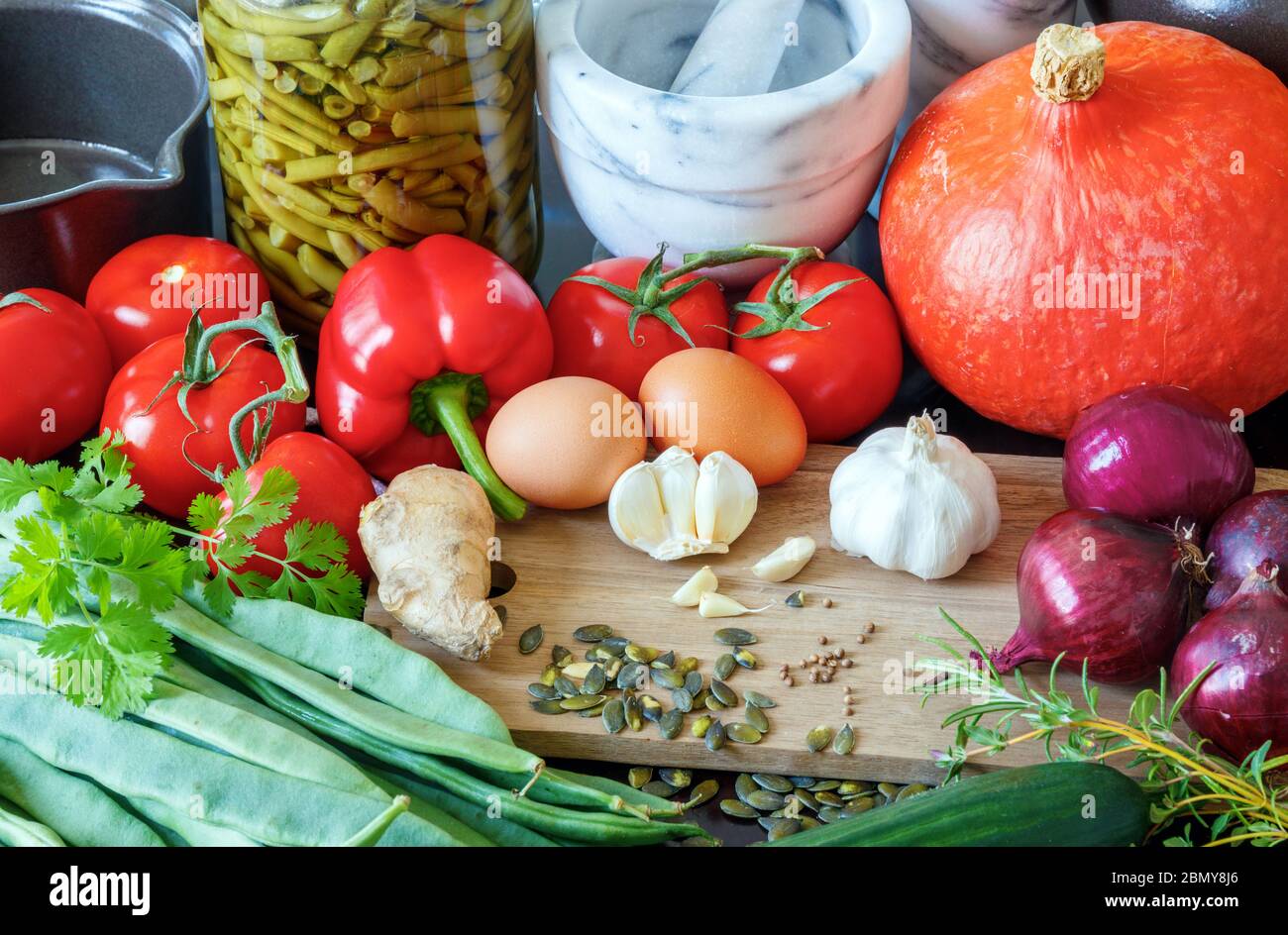 Zusammensetzung aus gesunder Gemüse, Kräutern, Gewürzen, Samen, Eiern und Kochutensilien. Stockfoto